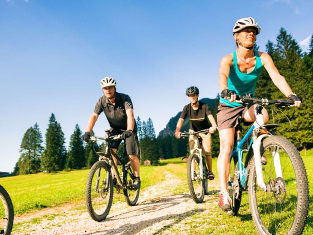 Symbolbild Kalorienverbrauch beim Sport: Eine Familie fährt mit den Fahrrad durch die Berge