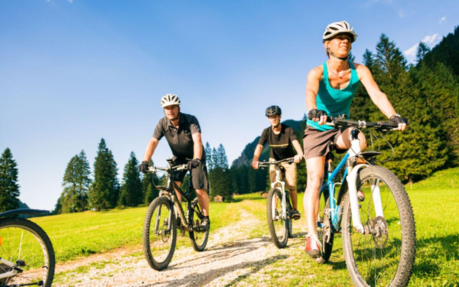 Symbolbild Kalorienverbrauch beim Sport: Eine Familie fährt mit den Fahrrad durch die Berge
