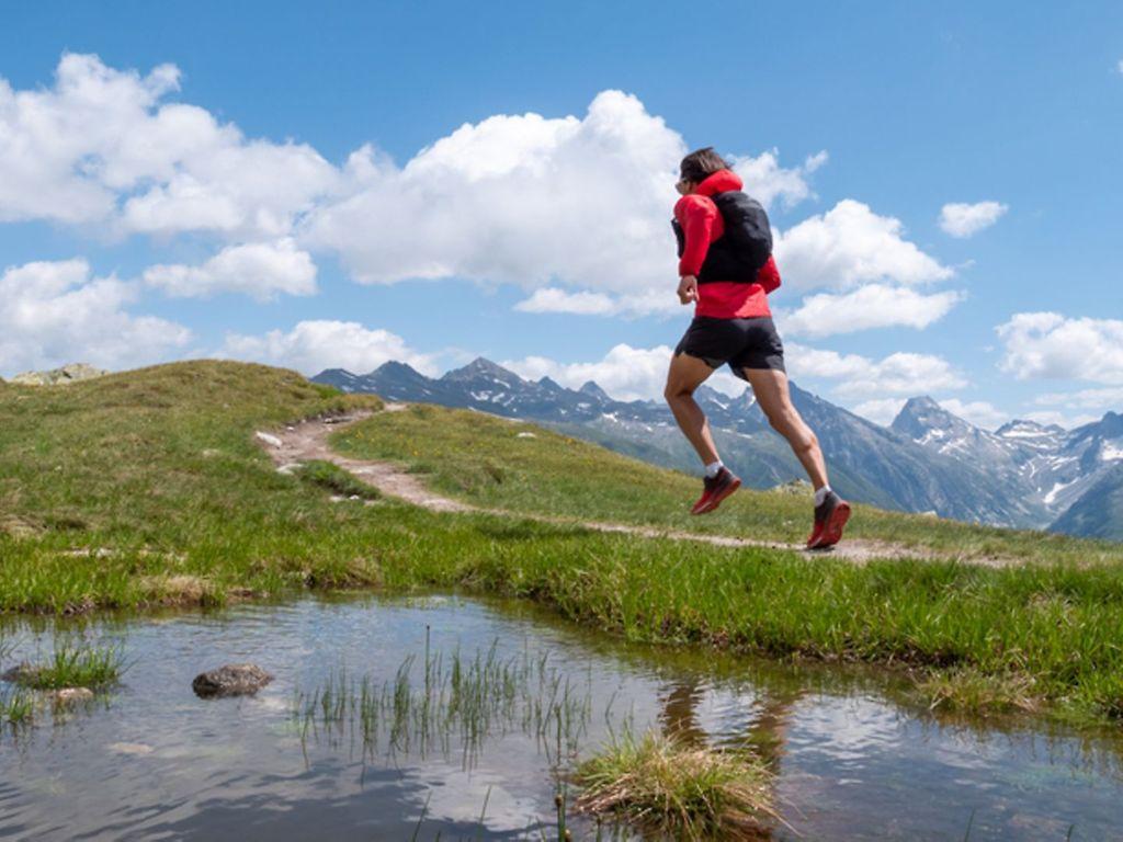 Trailrunning: Ein Trailrunner läuft durch eine sonnige Berglandschaft.