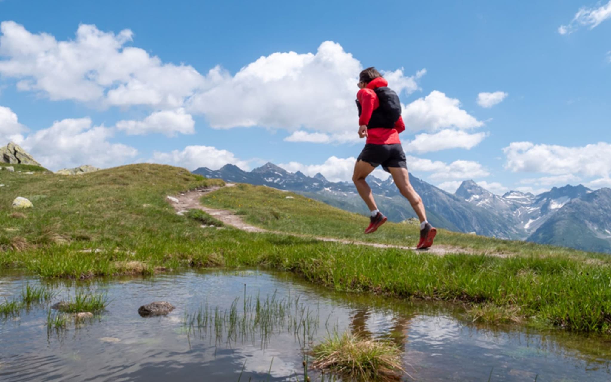 Trailrunning: Ein Trailrunner läuft durch eine sonnige Berglandschaft.