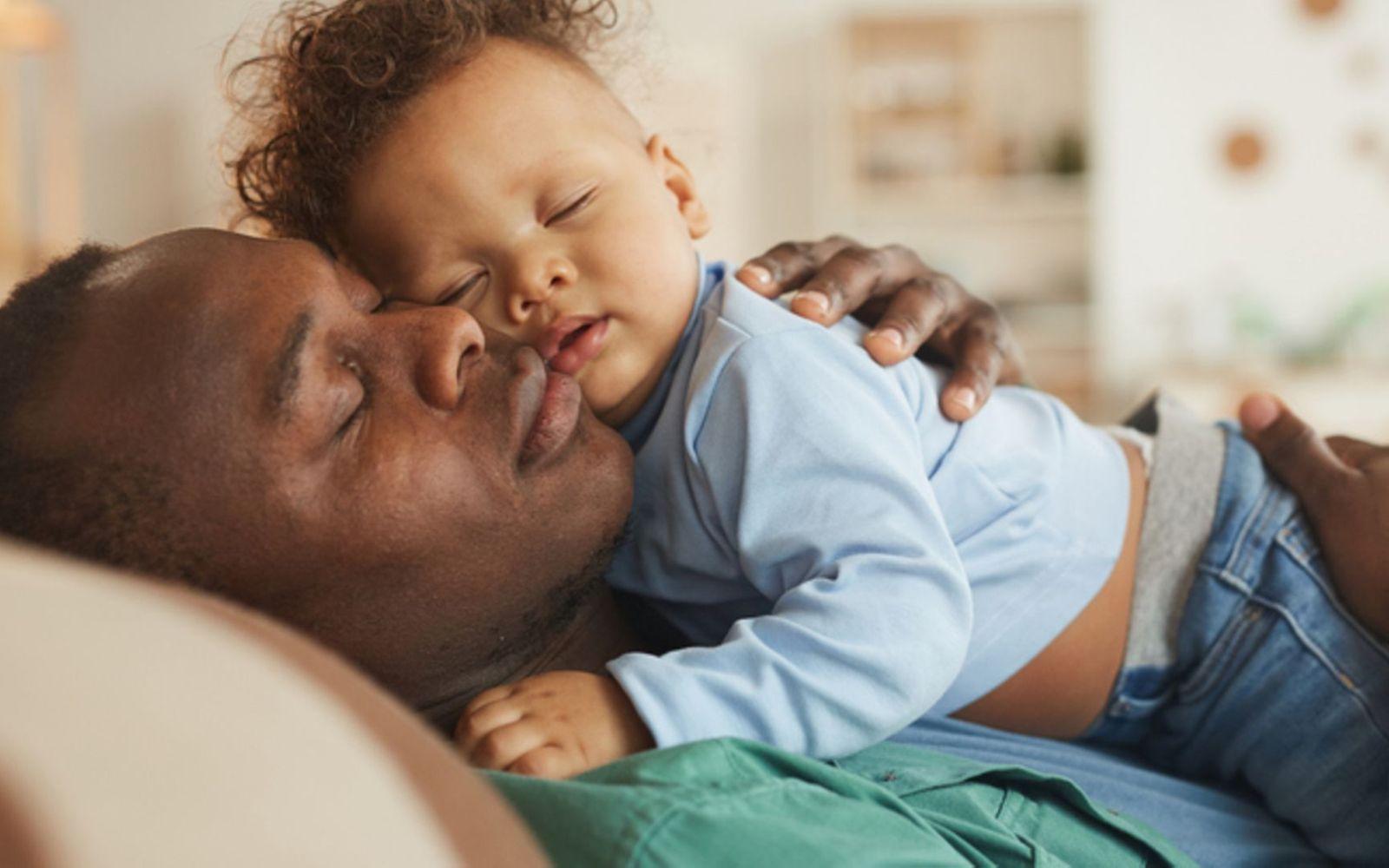 Babyschlaf: Vater schläft mit seinem Baby im Arm