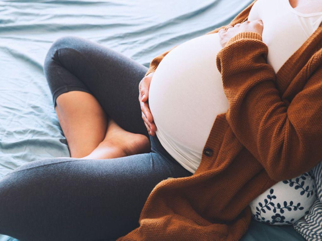 Blutungen in der Schwangerschaft: Eine Schwangere legt beide Hände auf ihren Bauch
