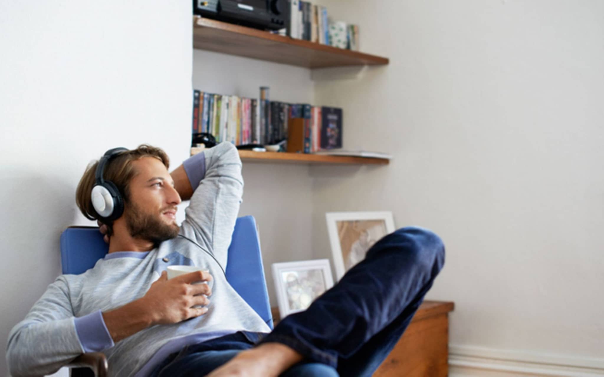 Hörprobleme: Ein Mann sitzt in einem Sessel und hört über einen Kopfhörer Musik.