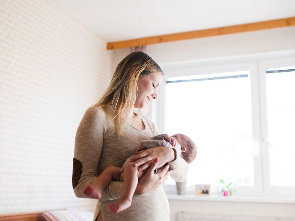 Körper nach der Geburt: Eine Mutter hält ihr neugeborenes Baby im Arm
