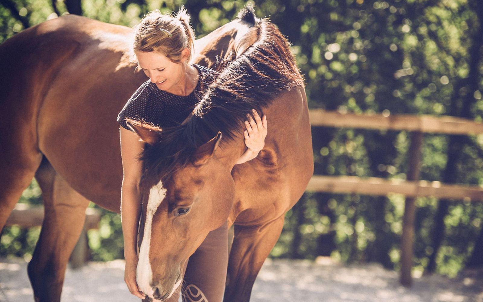 Reiten für die Gesundheit: Eine Frau streichelt ihr Pferd.