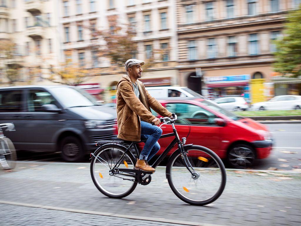 Herz-Kreislauf-Erkrankungen: Mann fährt mit dem Rad durch eine Stadt.