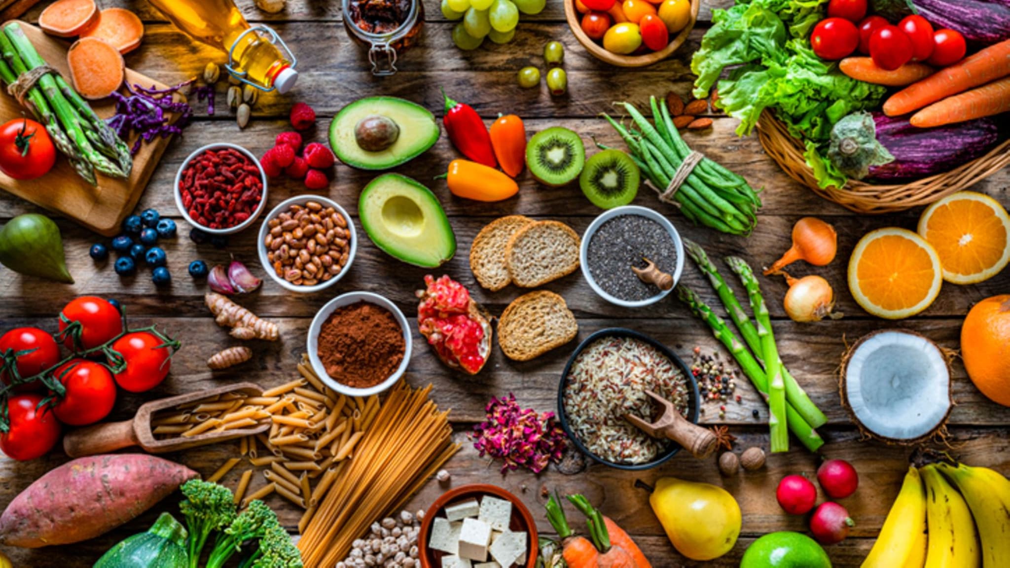 Vitamine: Tisch voll bunter, frischer Lebensmittel wie Kiwis, Himbeeren, Orangen