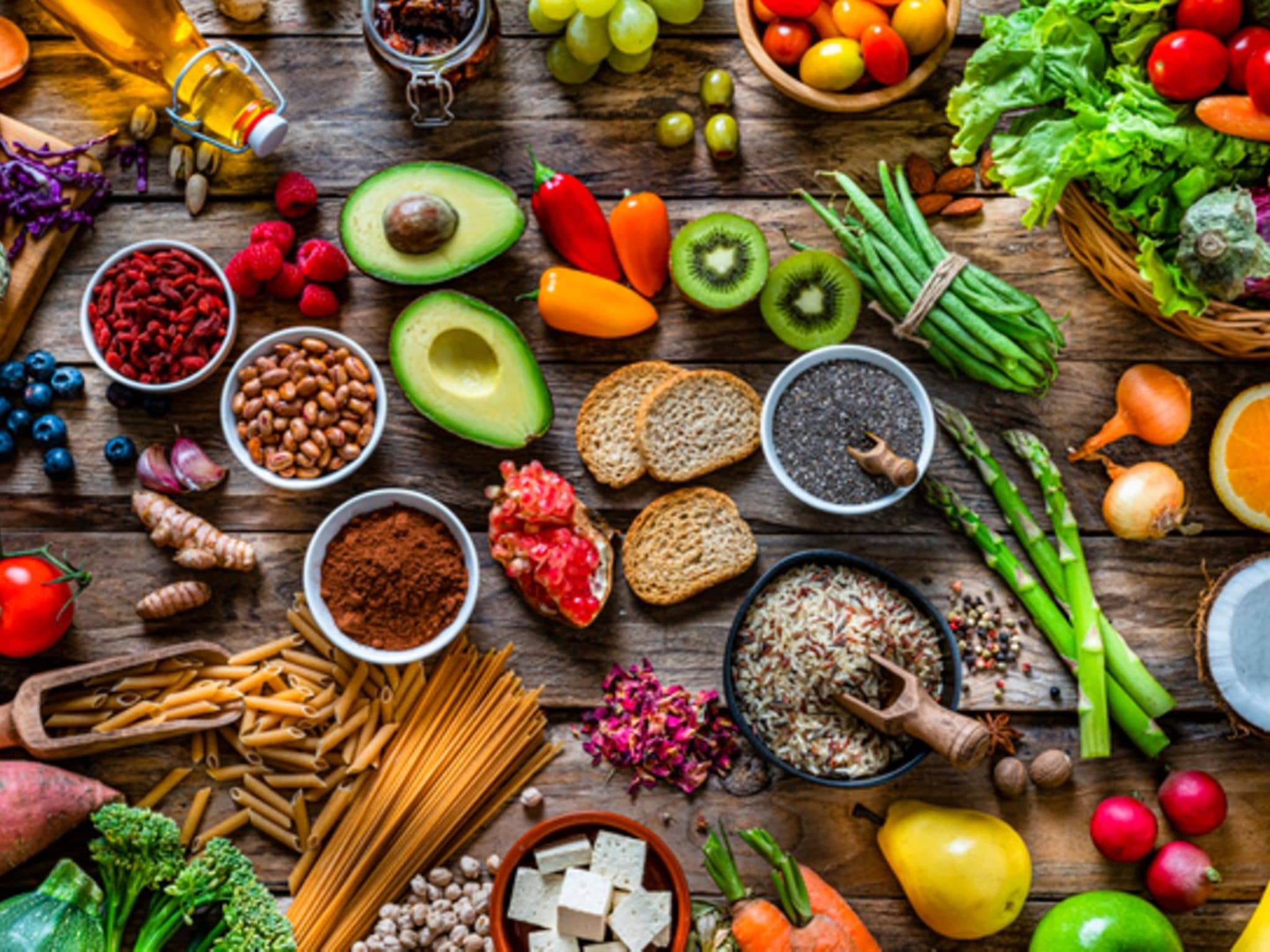 Vitamine: Tisch voll bunter, frischer Lebensmittel wie Kiwis, Himbeeren, Orangen