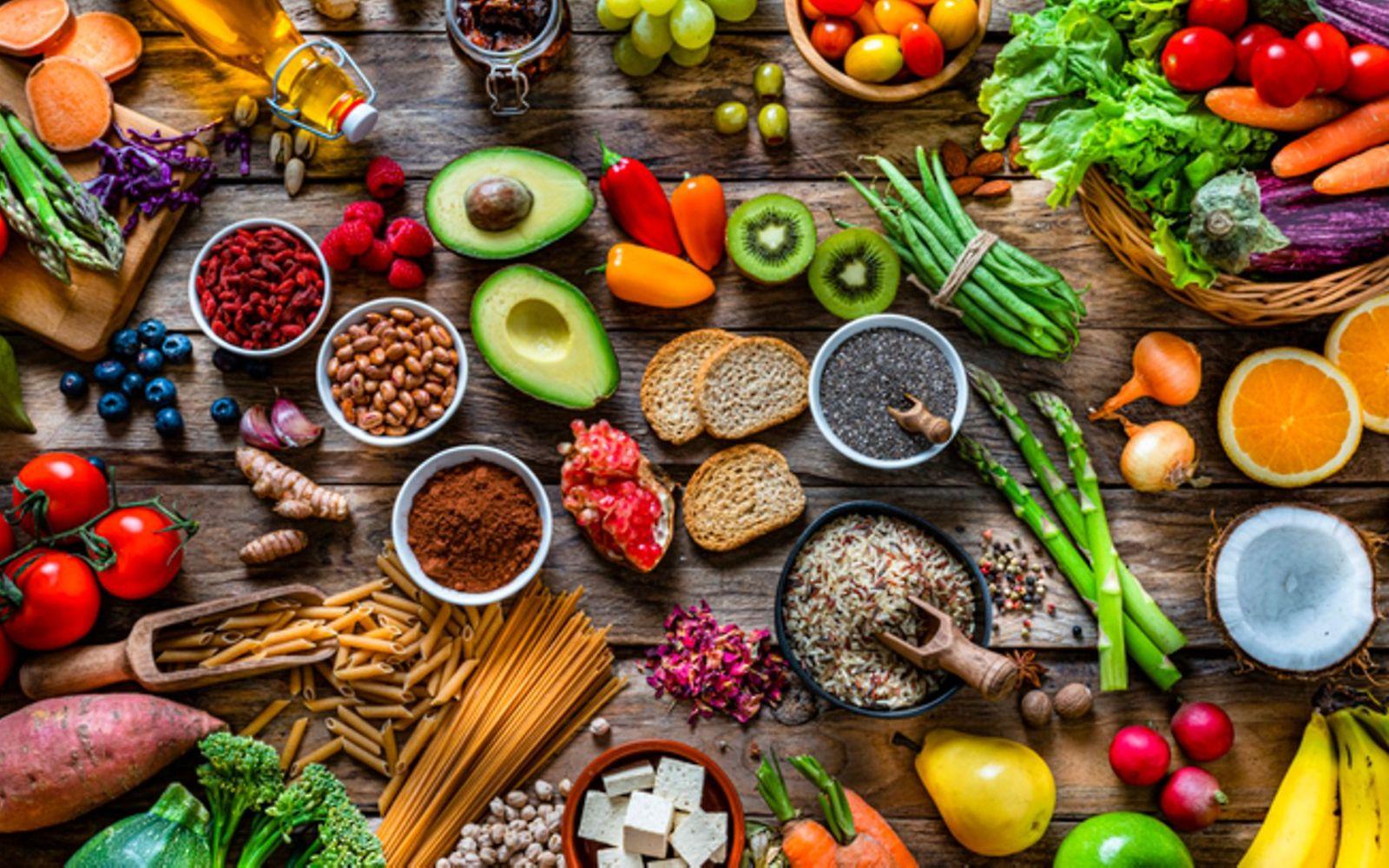 Vitamine: Tisch voll bunter, frischer Lebensmittel wie Kiwis, Himbeeren, Orangen