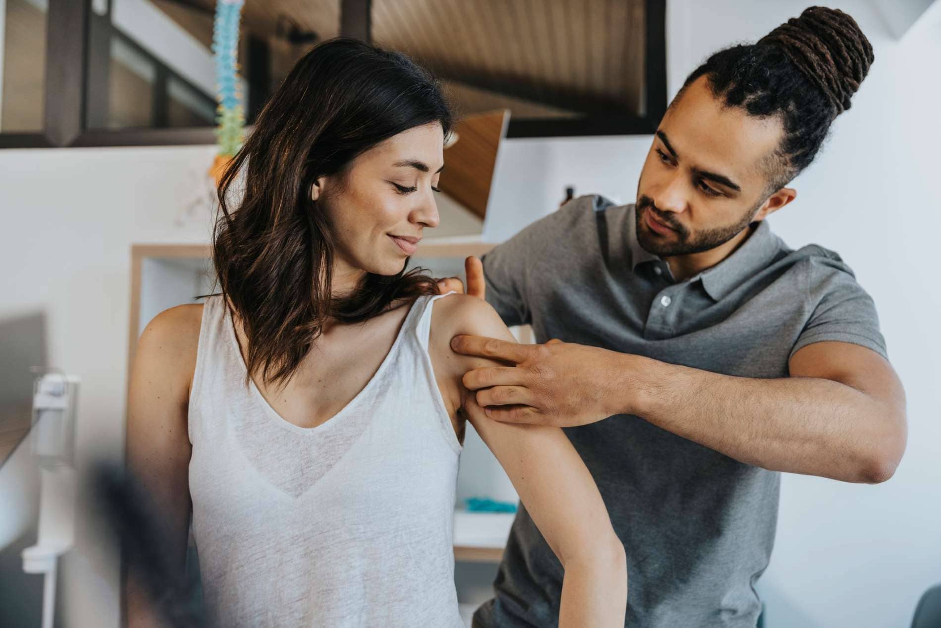 Heilmittel: Mann behandelt Frau an Schulter.