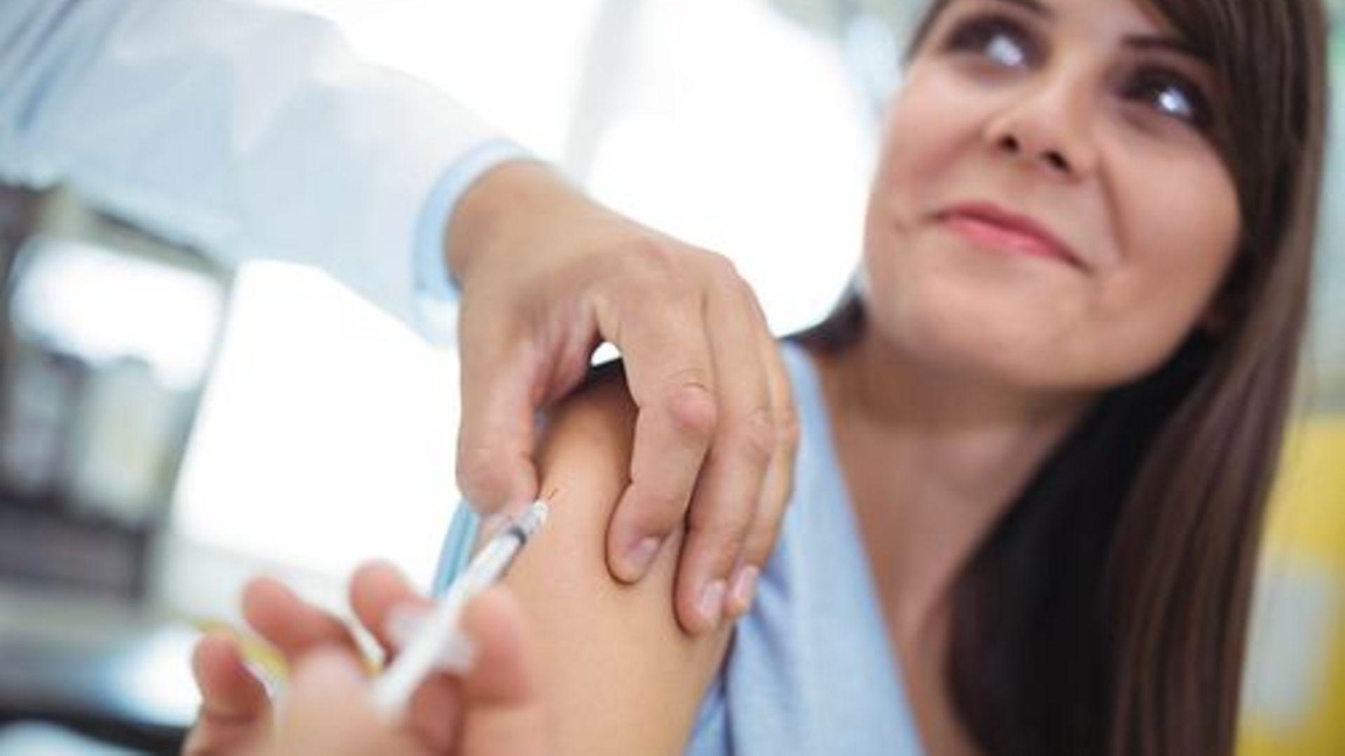 Impfungen für Erwachsene: Junge Frau erhält Spritze in den Oberarm.