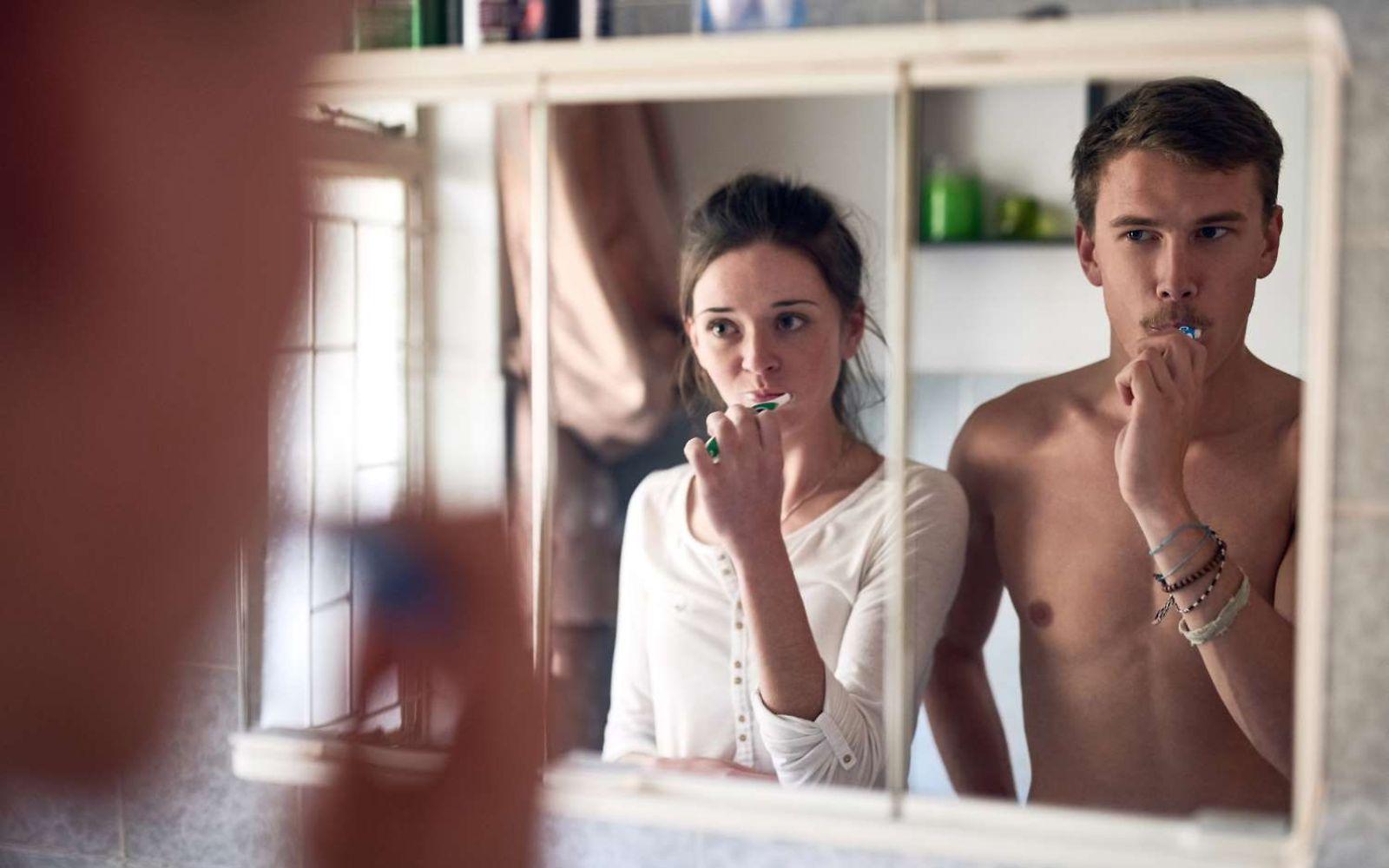 Zahnpflege: Junges Paar putzt gemeinsam vor einem Spiegel die Zähne.
