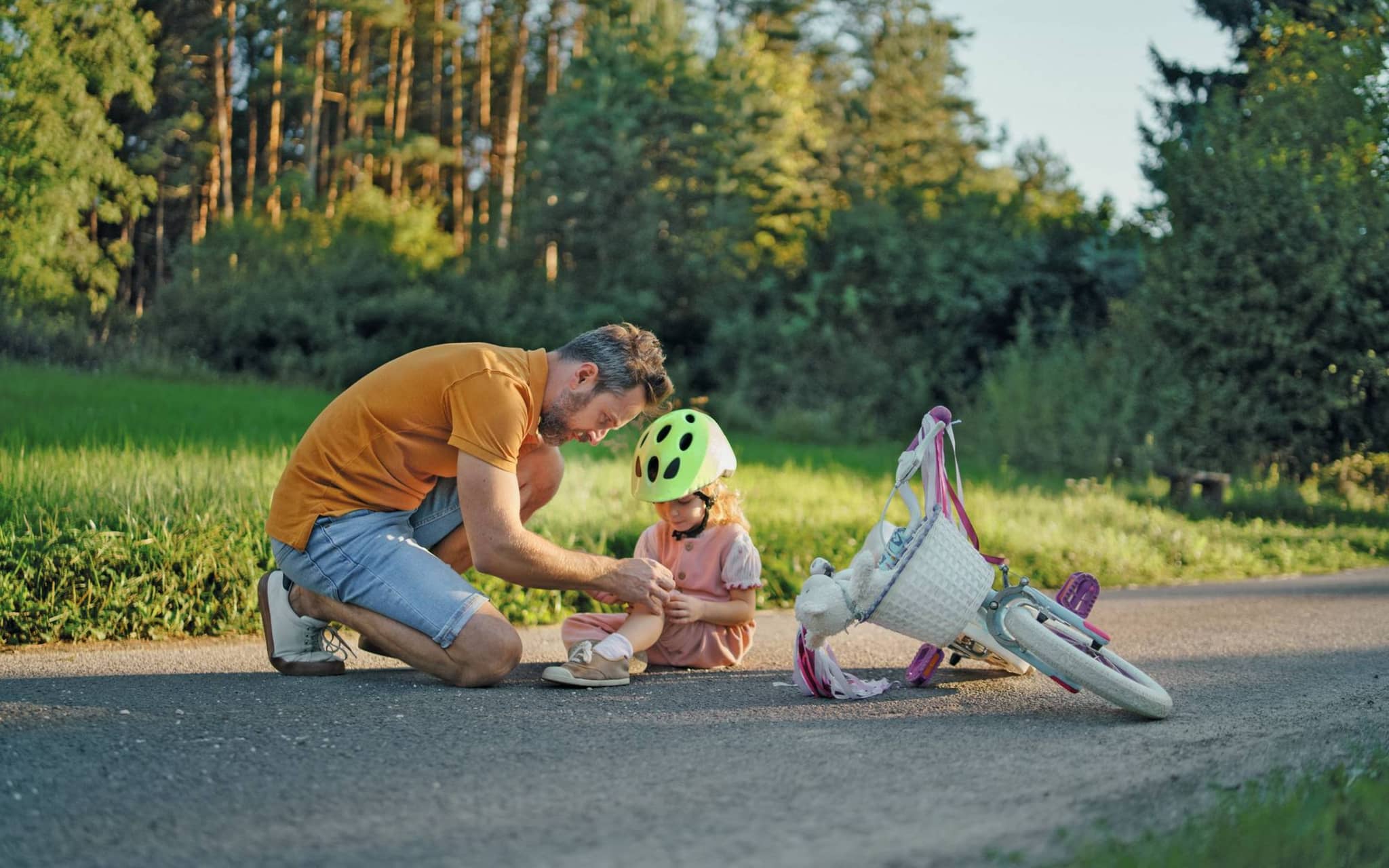 Ein Vater versorgt seine Tochter nachdem sie mit dem Fahrrad gestürzt ist.