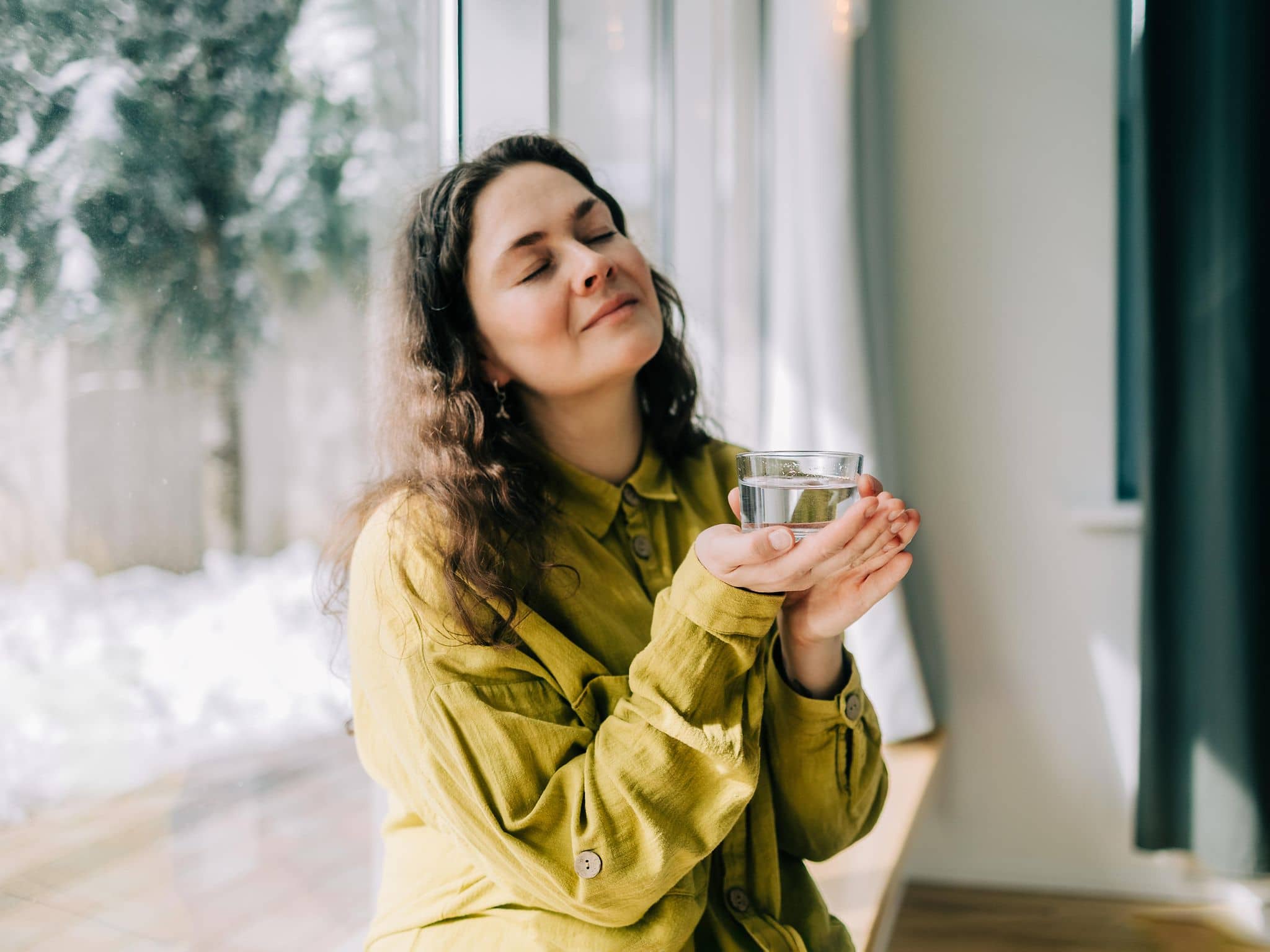 Junge Frau ruht sich mit einem Glas Wasser in der Hand aus.