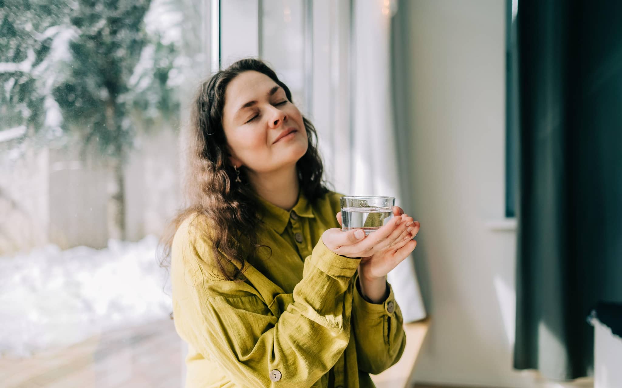 Junge Frau ruht sich mit einem Glas Wasser in der Hand aus.