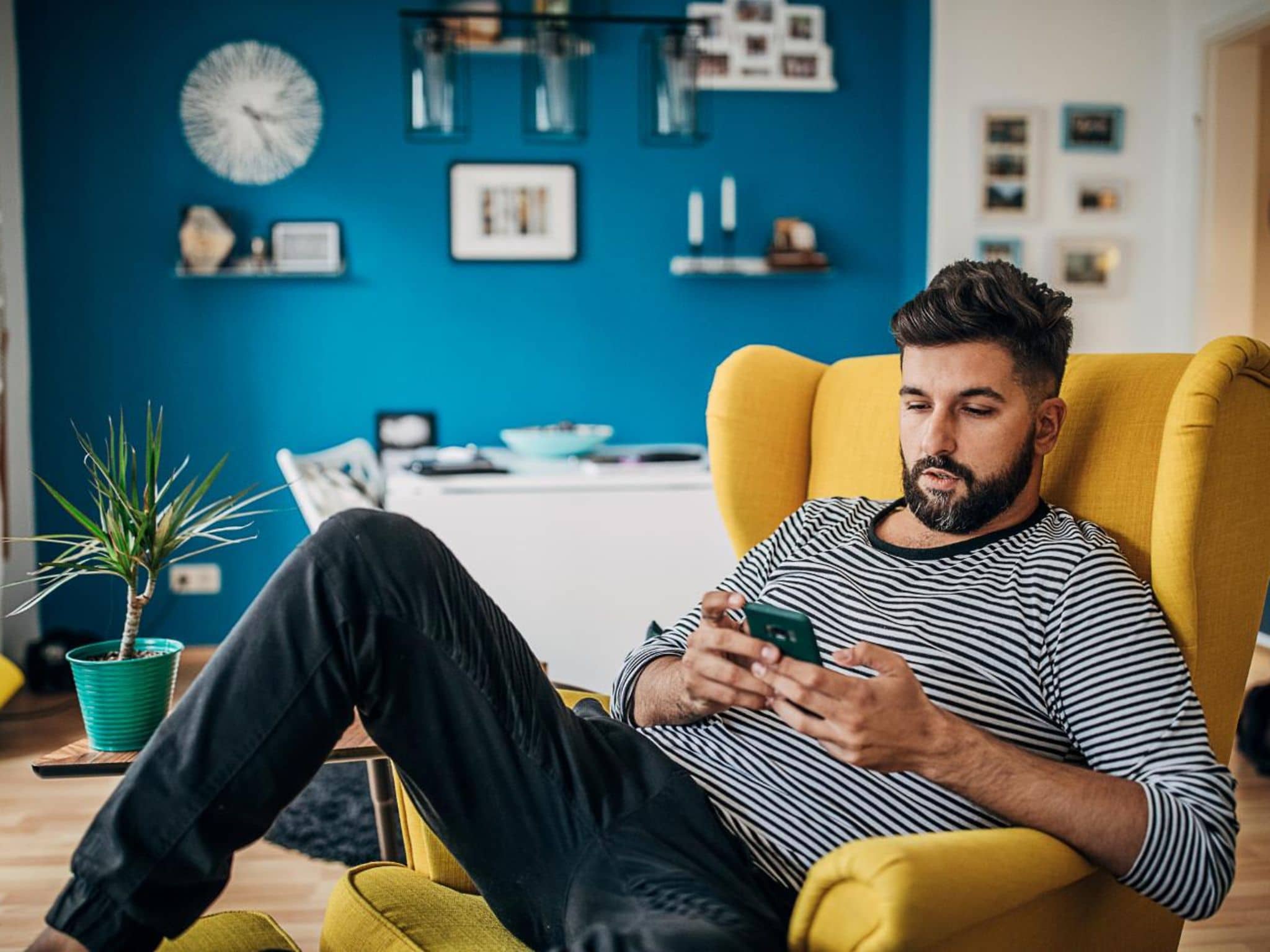 DAK uygulaması: Koltukta oturan bir adam akıllı telefonunu kullanıyor