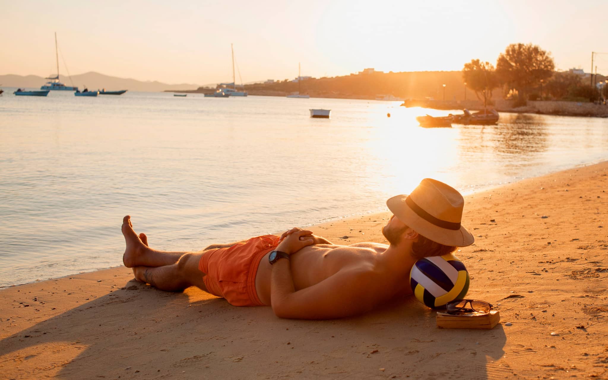 Mann entspannt am Strand in der Abendsonne.