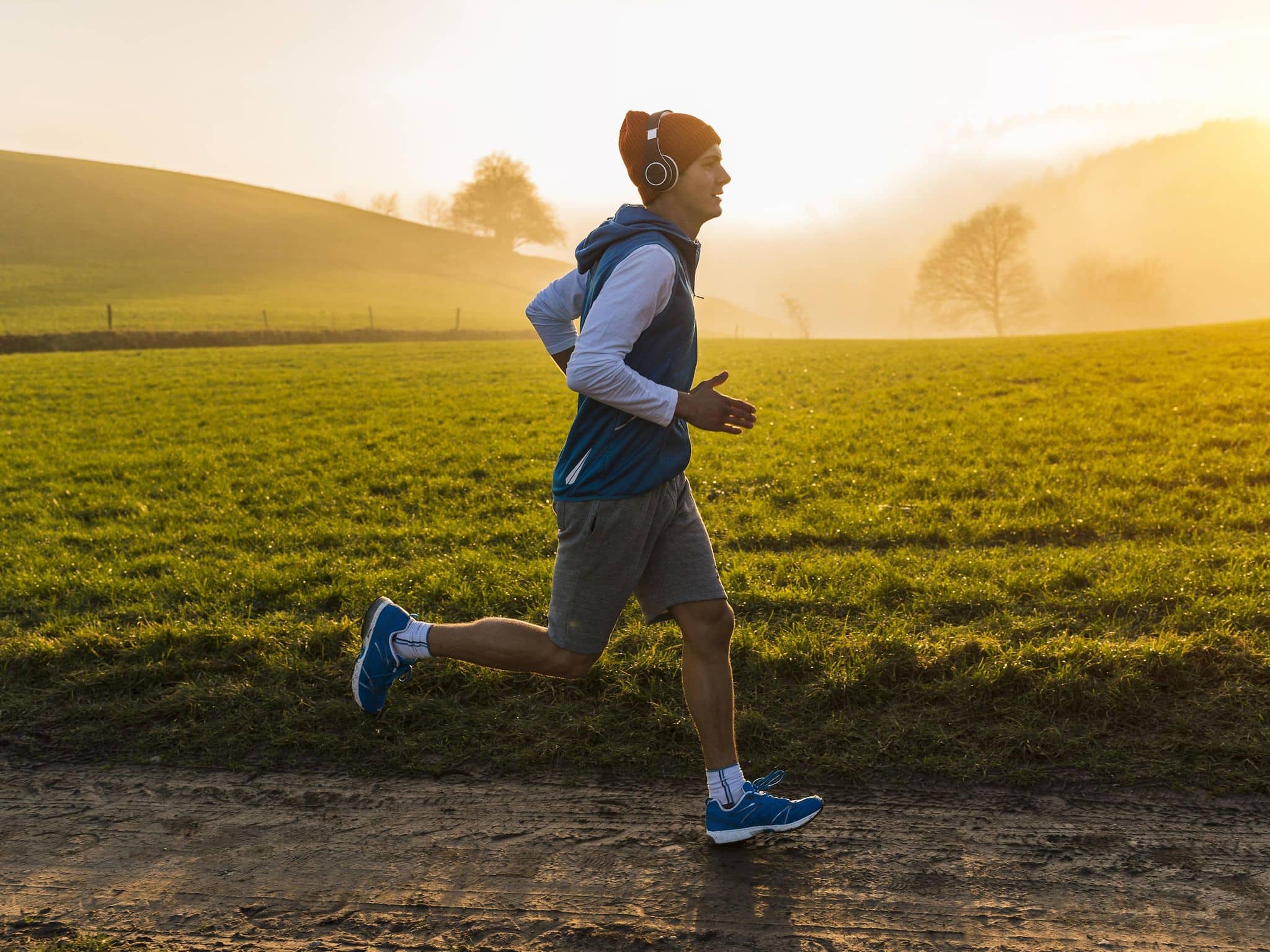 Junger Mann joggt morgens auf dem Feld.
