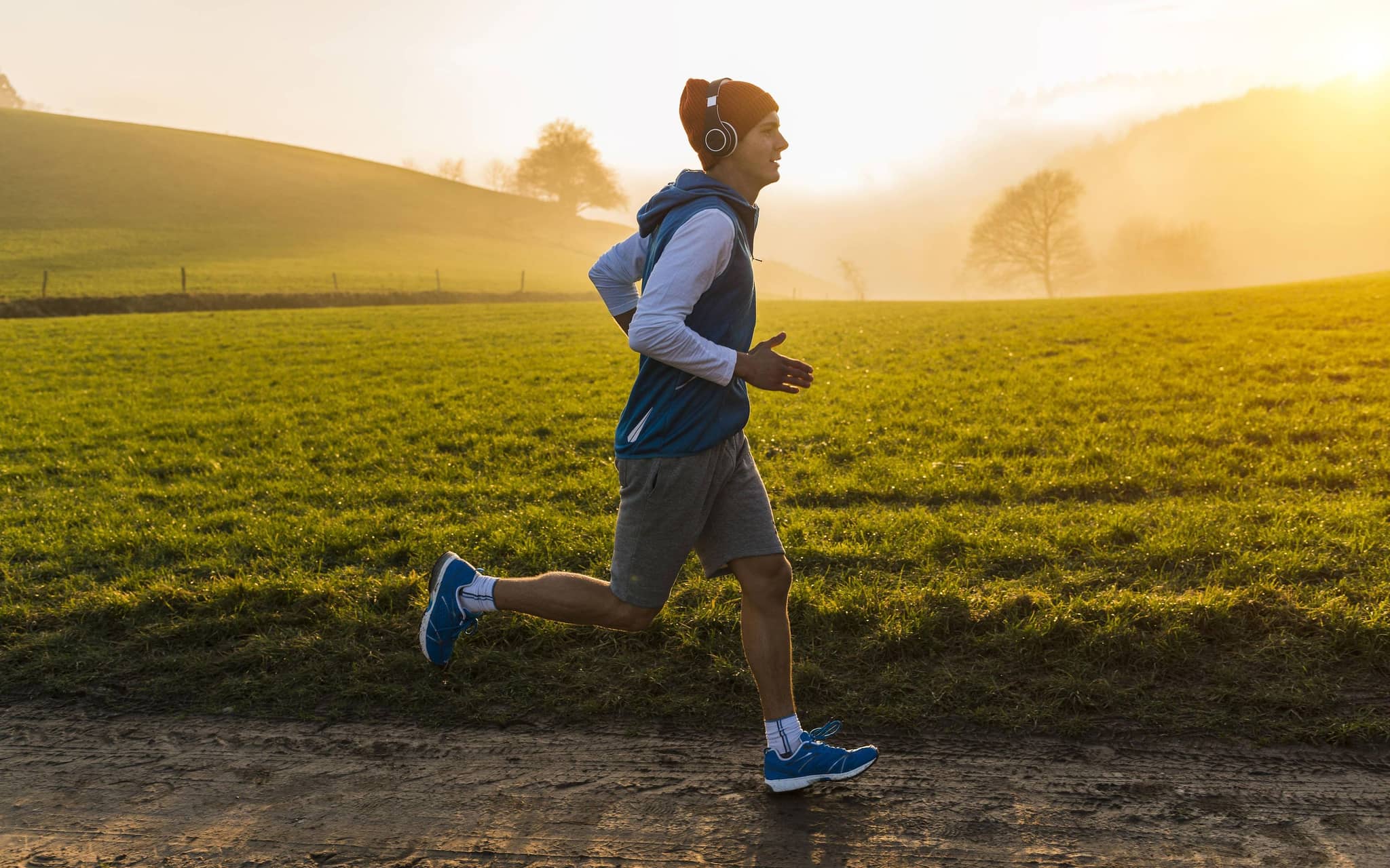 Junger Mann joggt morgens auf dem Feld.