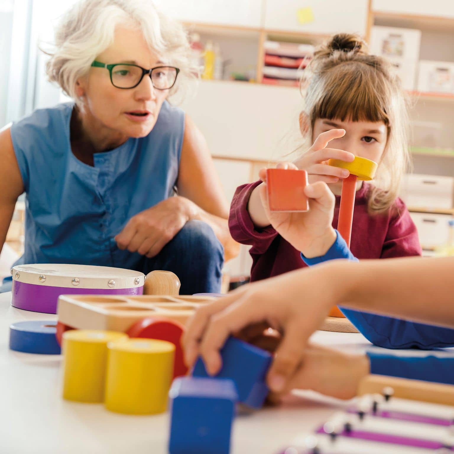 Ältere Frau arbeitet im Kindergarten mit Kindern.