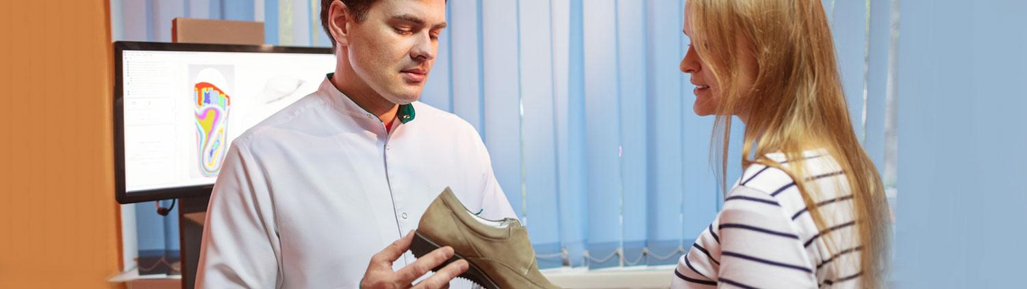 Orthopädische Schuhe: Mann hält einen Schuh in der Hand und betrachtet ihn.