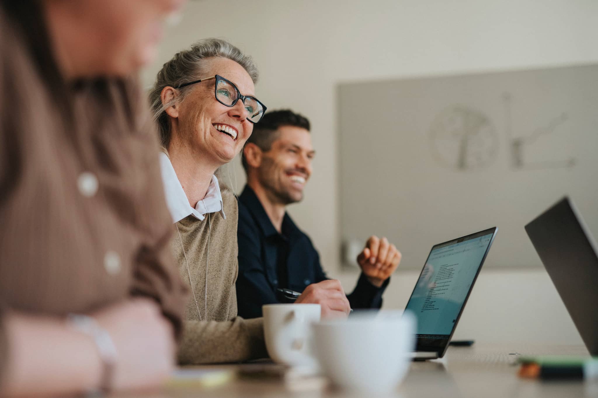 Arbeitsmeeting - eine Frau und ein Mann sitzen fröhlich am Tisch