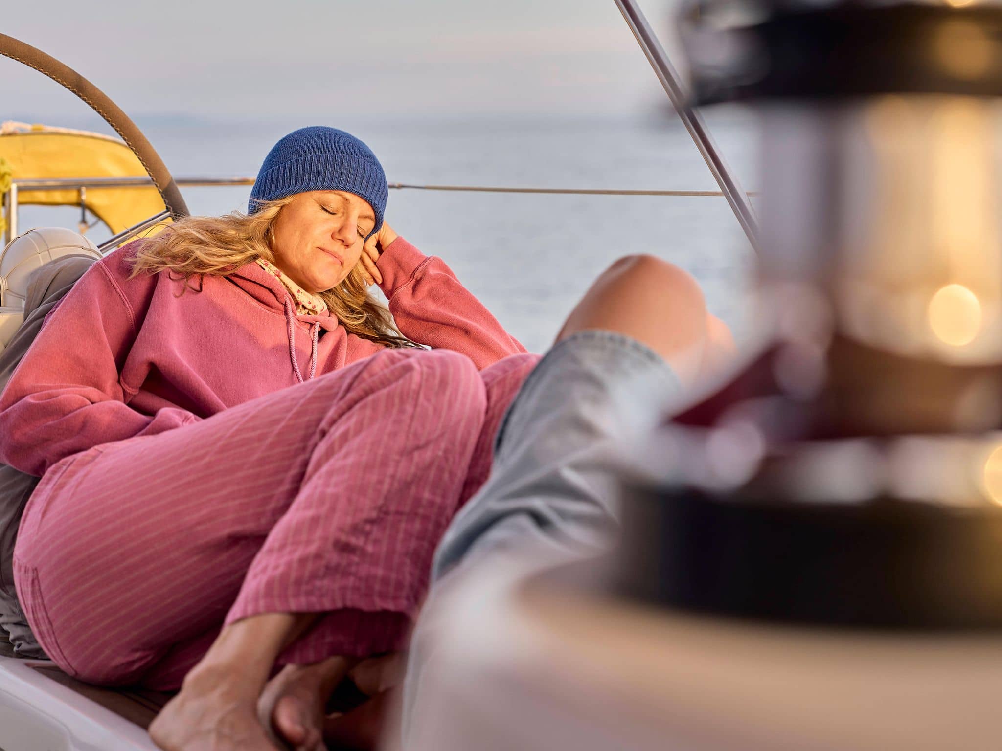 Frau schläft in Kleidung auf dem Deck eines Bootes.