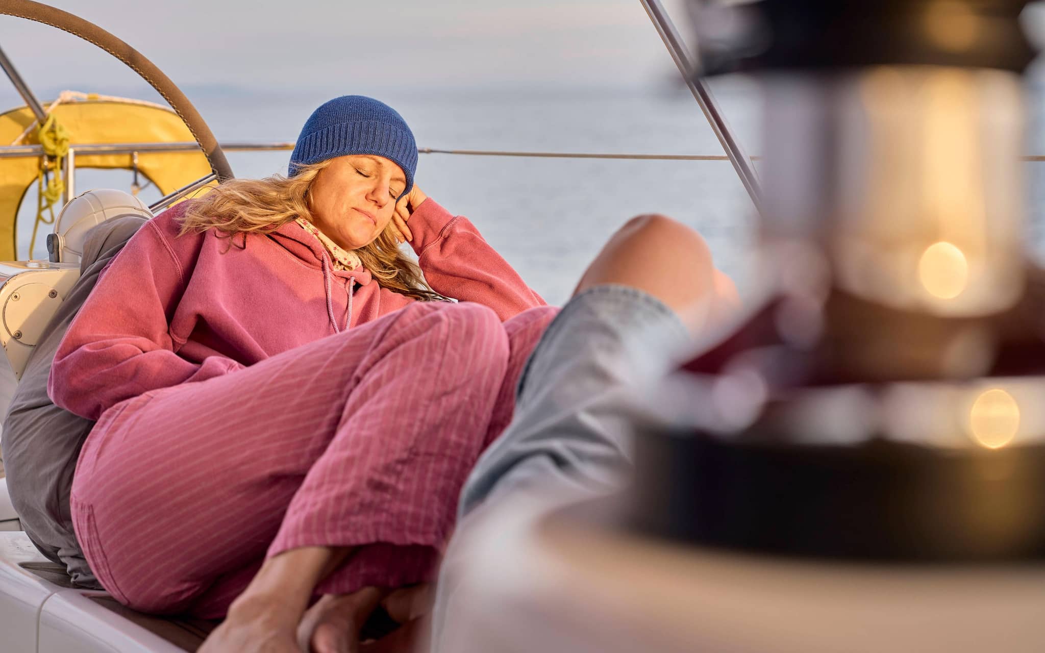 Frau schläft in Kleidung auf dem Deck eines Bootes.