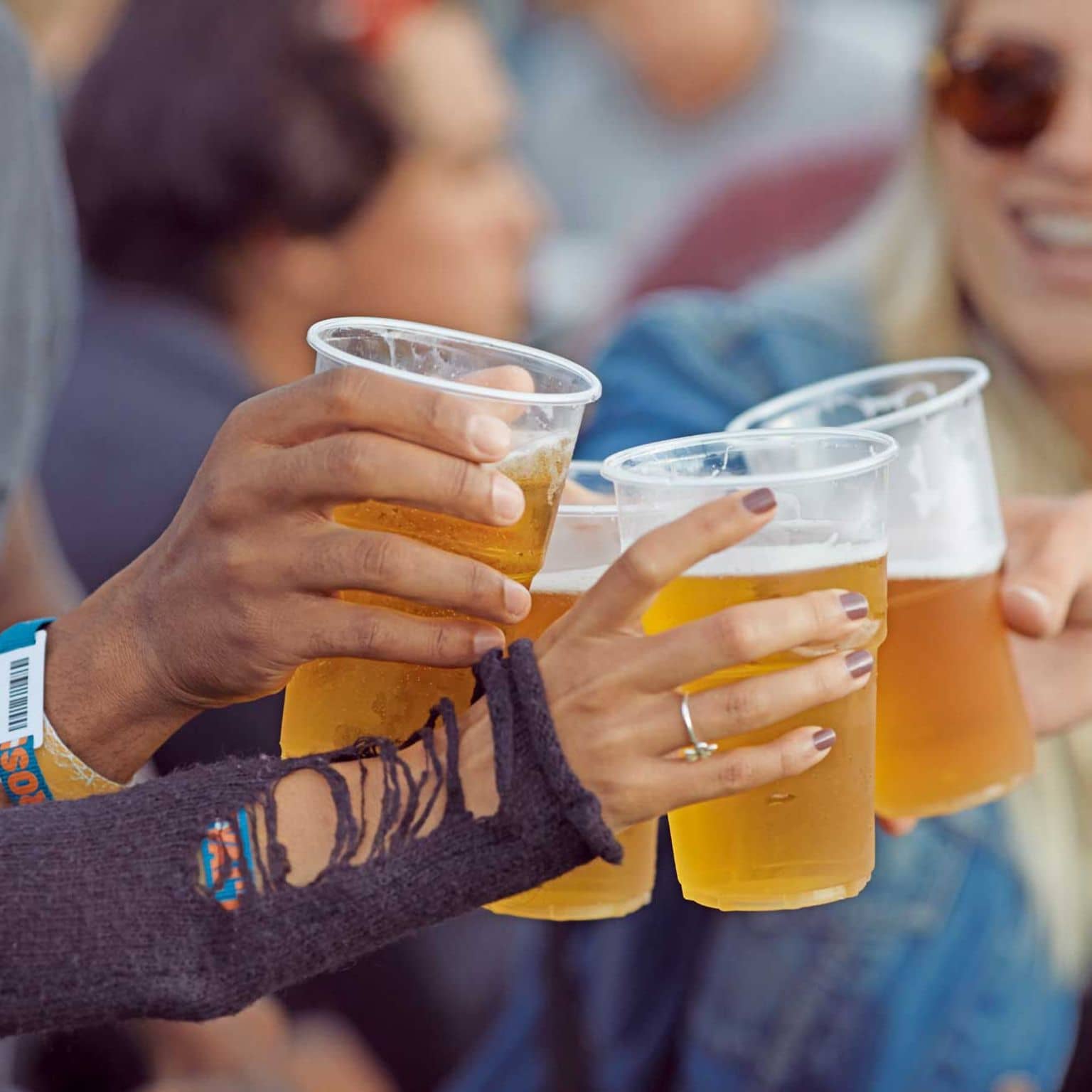Nahaufnahme von Händen, die mit Bechern voll Bier anstoßen