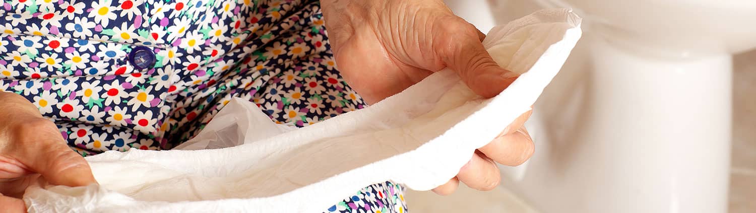 Saugende Inkontinenzhilfen: Ältere Frau hält Inkontinenzvorlage in der Hand.