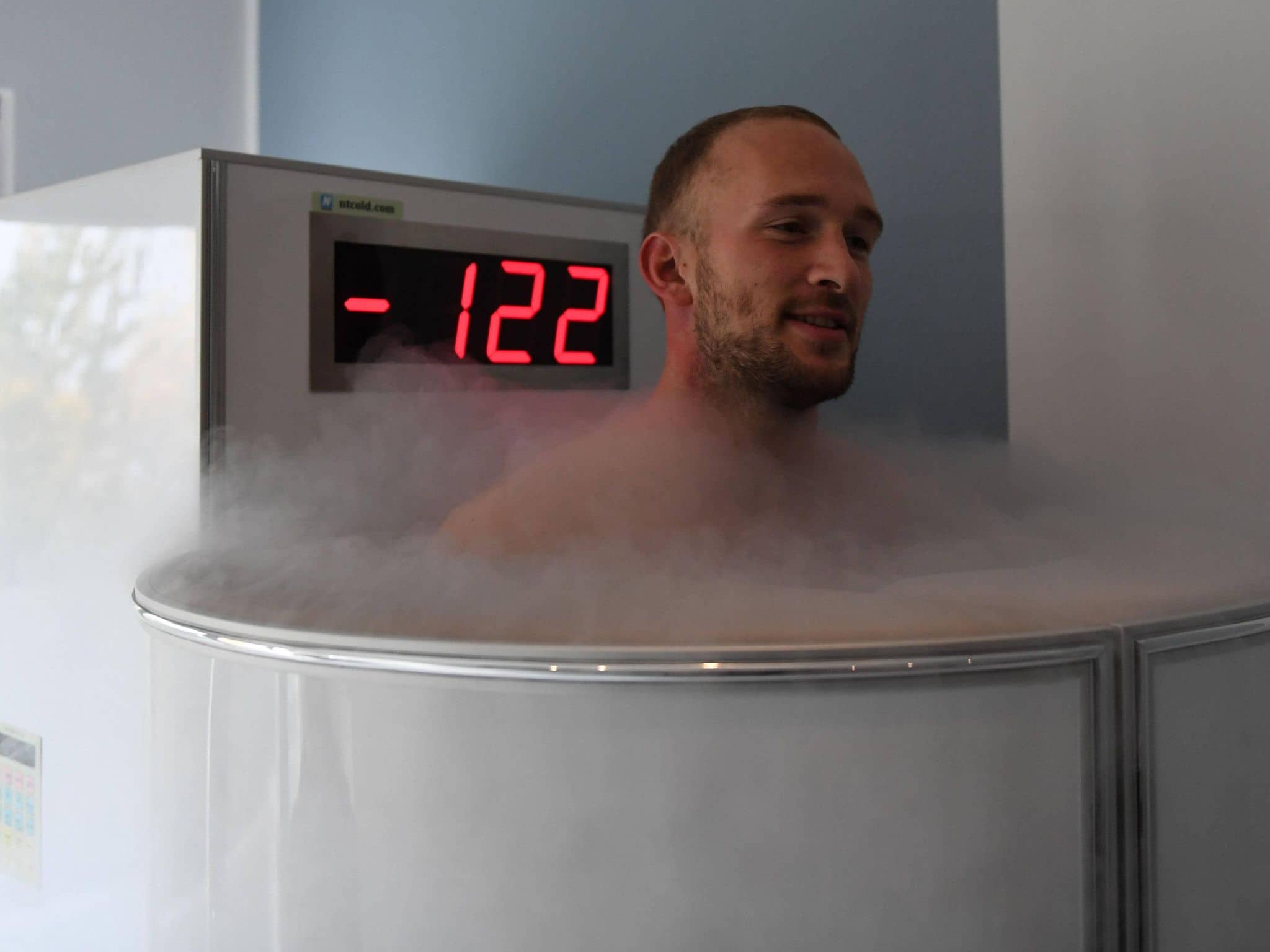 Ein Mann steht in einer Ganzkörper-Kältekammer, die eine Temperatur von minus 122 Grad anzeigt.