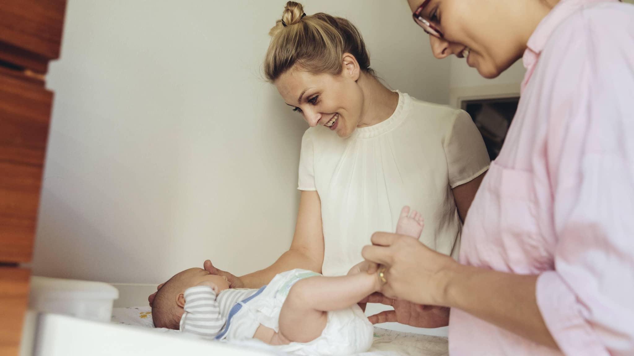 Hebamme mit Mutter und Baby am Wickeltisch