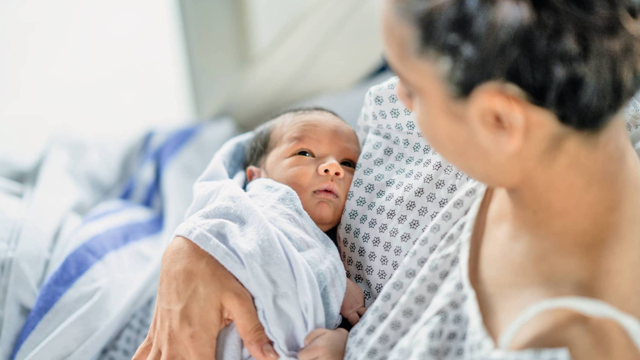 Frau im Geburtskittel mit Baby im Arm