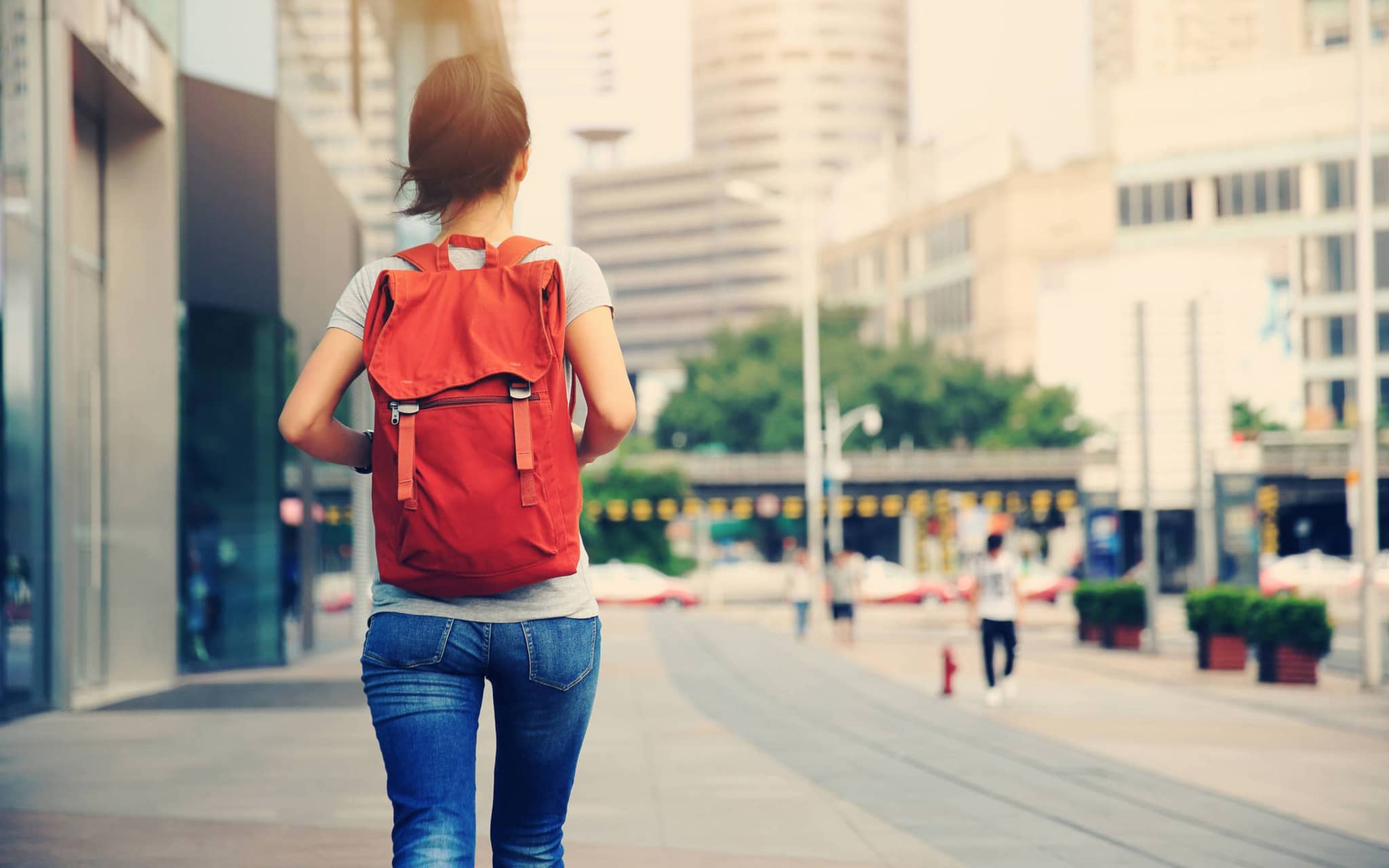 Hexenschuss: Junge Frau mit Rucksack von hinten in der Stadt.