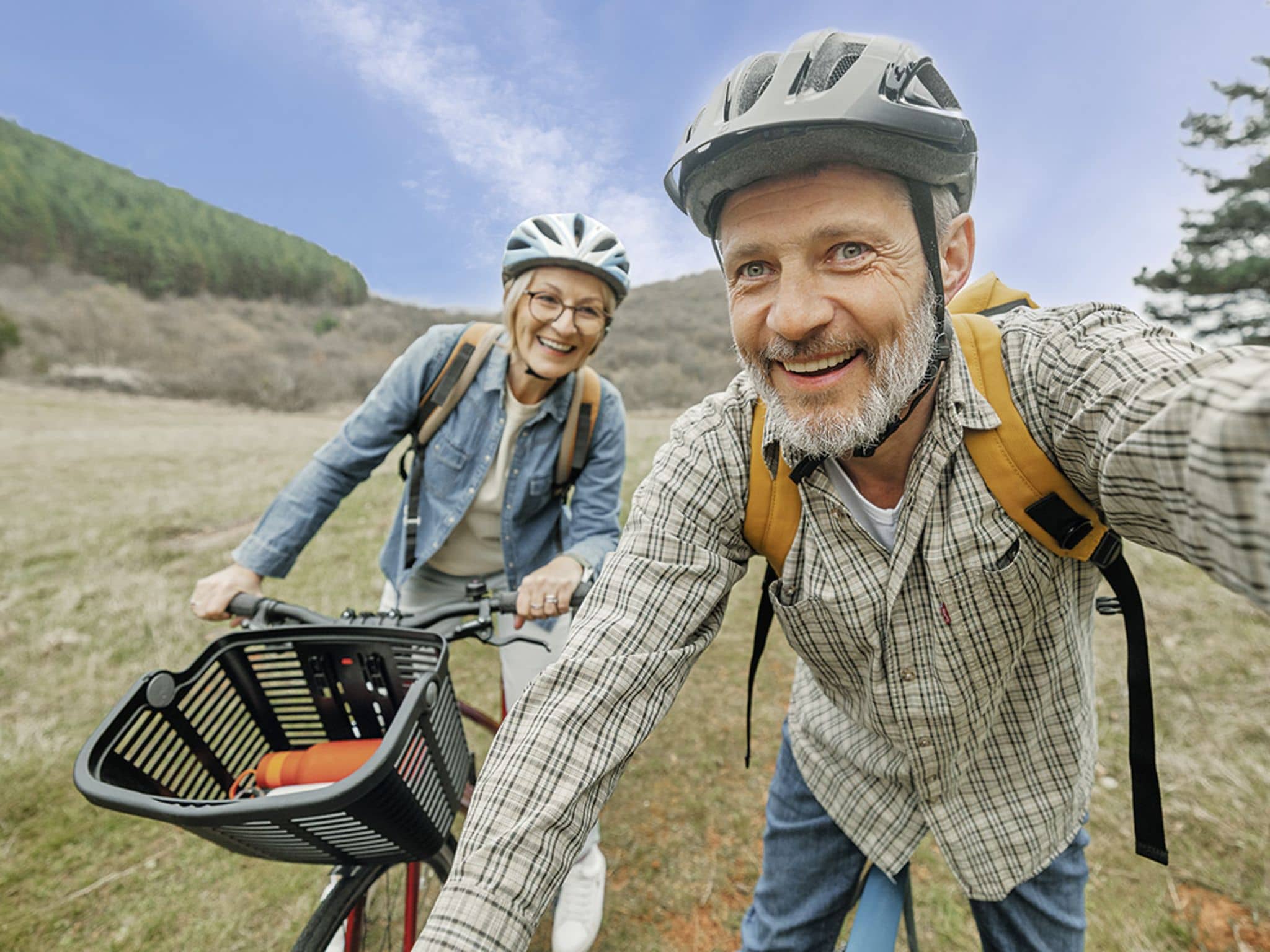 Longevity: Älteres Pärchen fährt mit dem Fahrrad durch eine Naturlandschaft.
