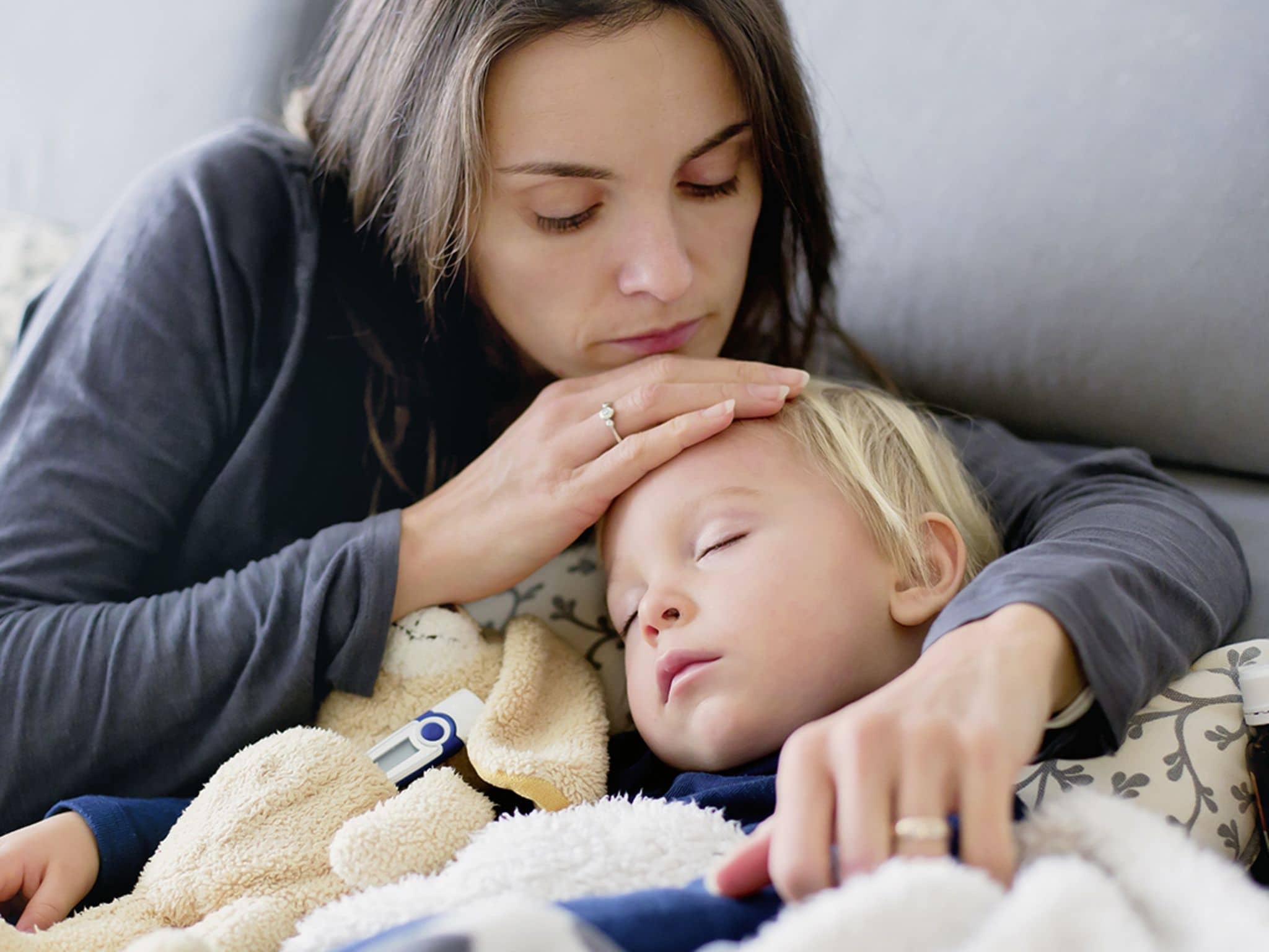 Elterncoaching: Eine Mutter hält ihr krankes schlafendes Kind im Arm.