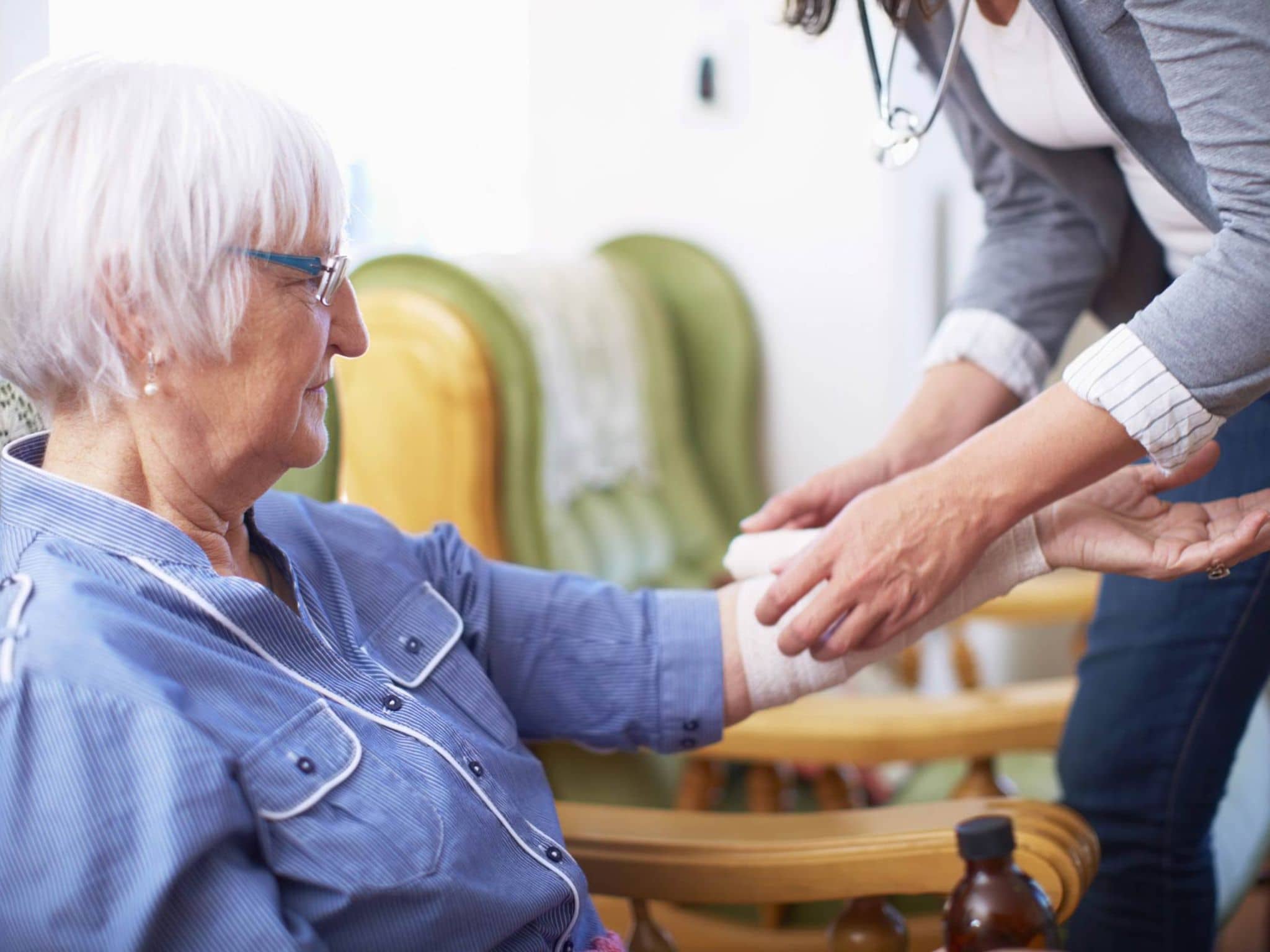 Verbandmittel: Ältere Frau bekommt einen Verband am Arm angelegt.
