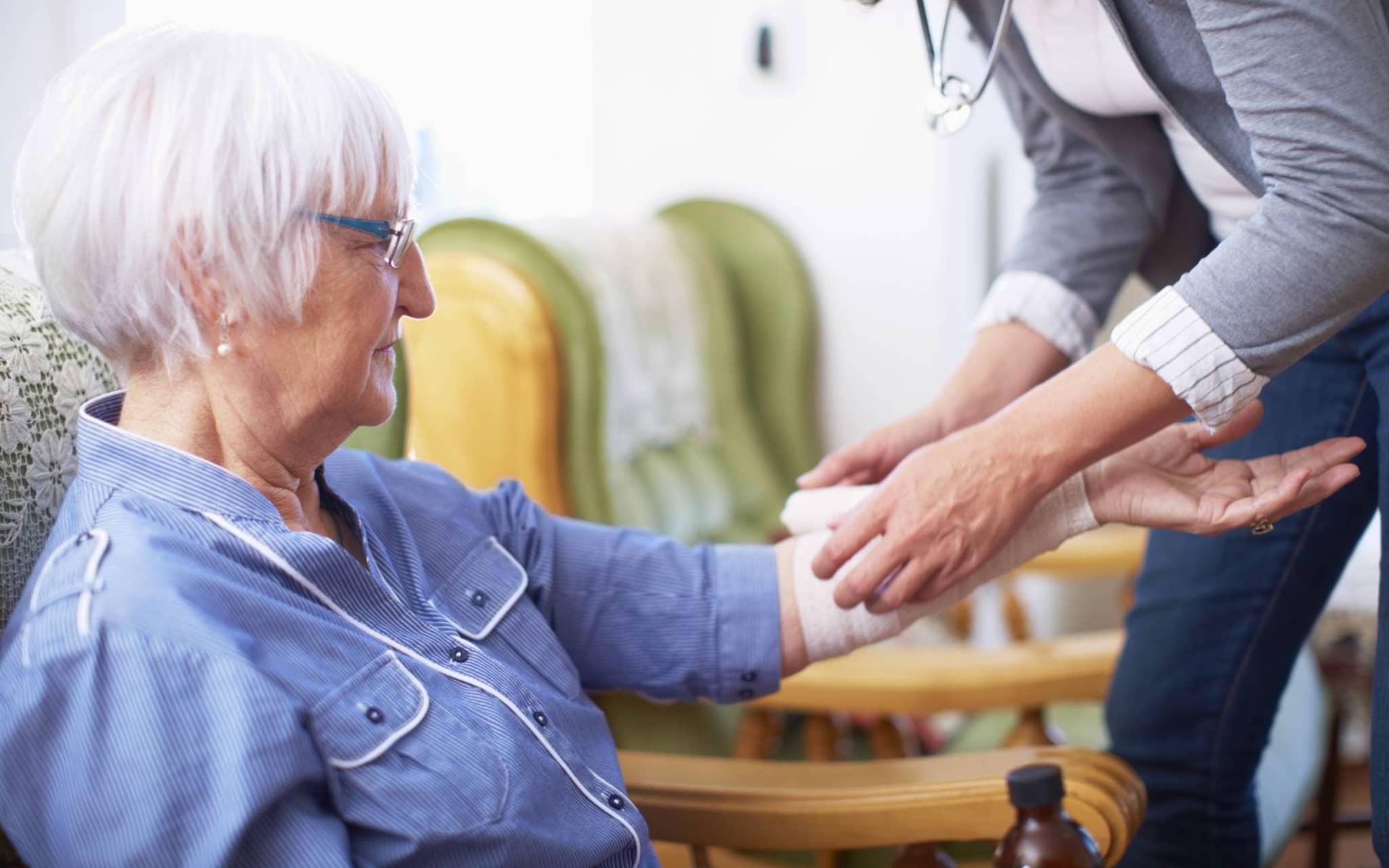 Verbandmittel: Ältere Frau bekommt einen Verband am Arm angelegt.