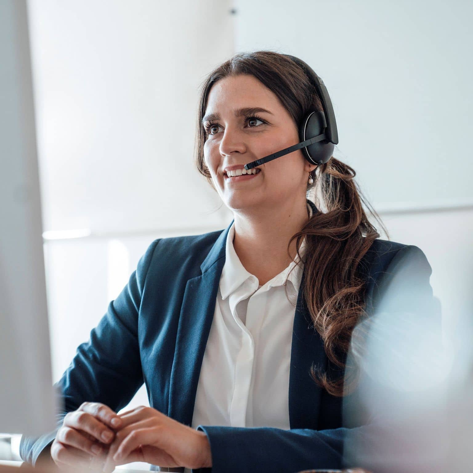 Eine Frau im Business Look berät telefonisch jemanden per Headset.