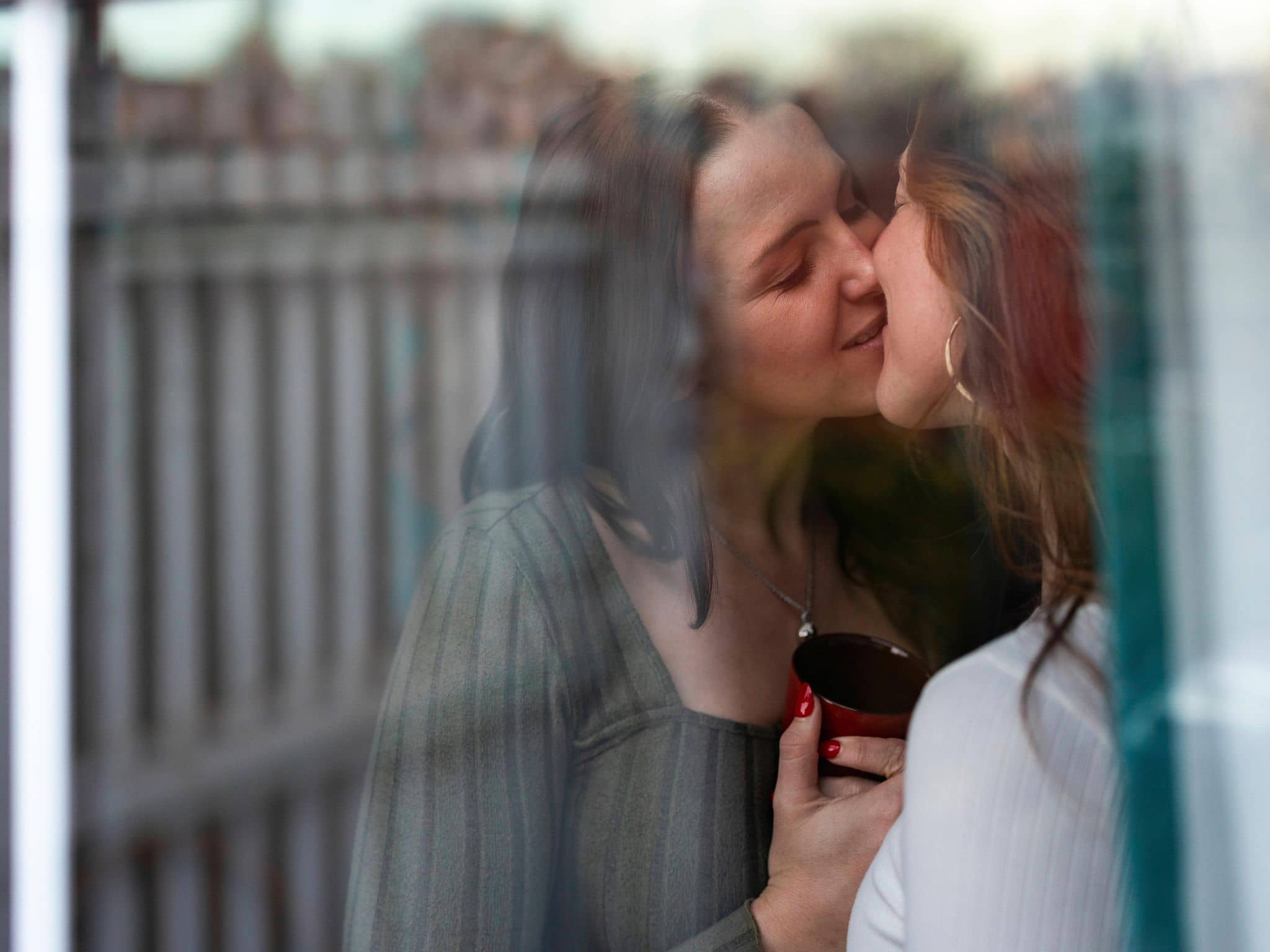 Zwei junge Frauen stehen am Fenster und küssen sich