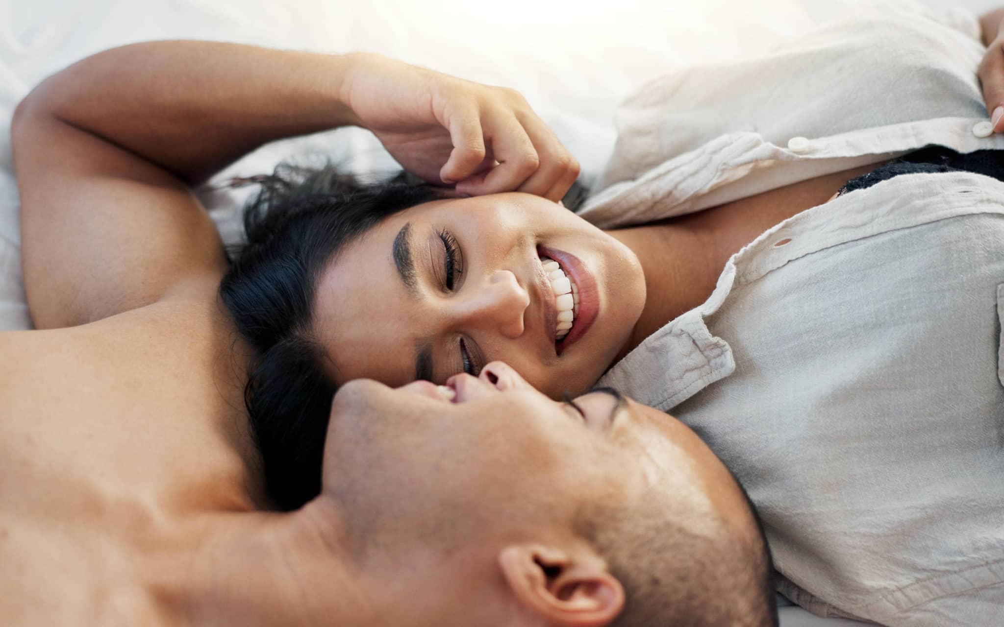 Paar im Bett, der Mann fasst der Frau zärtlich an die Wange