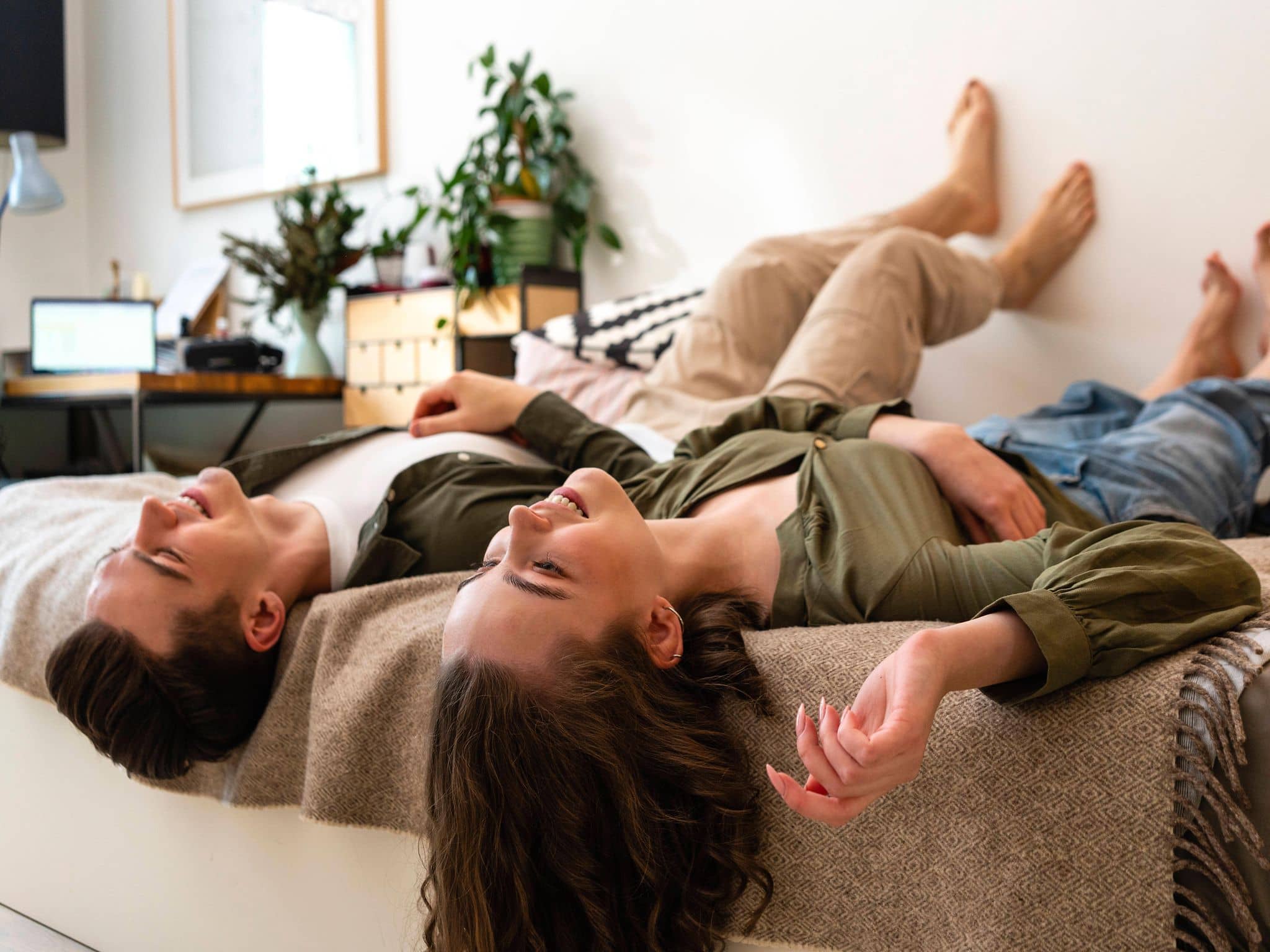 Junge und Mädchen liegen bekleidet nebeneinander im Bett und gucken vergnügt an die Decke