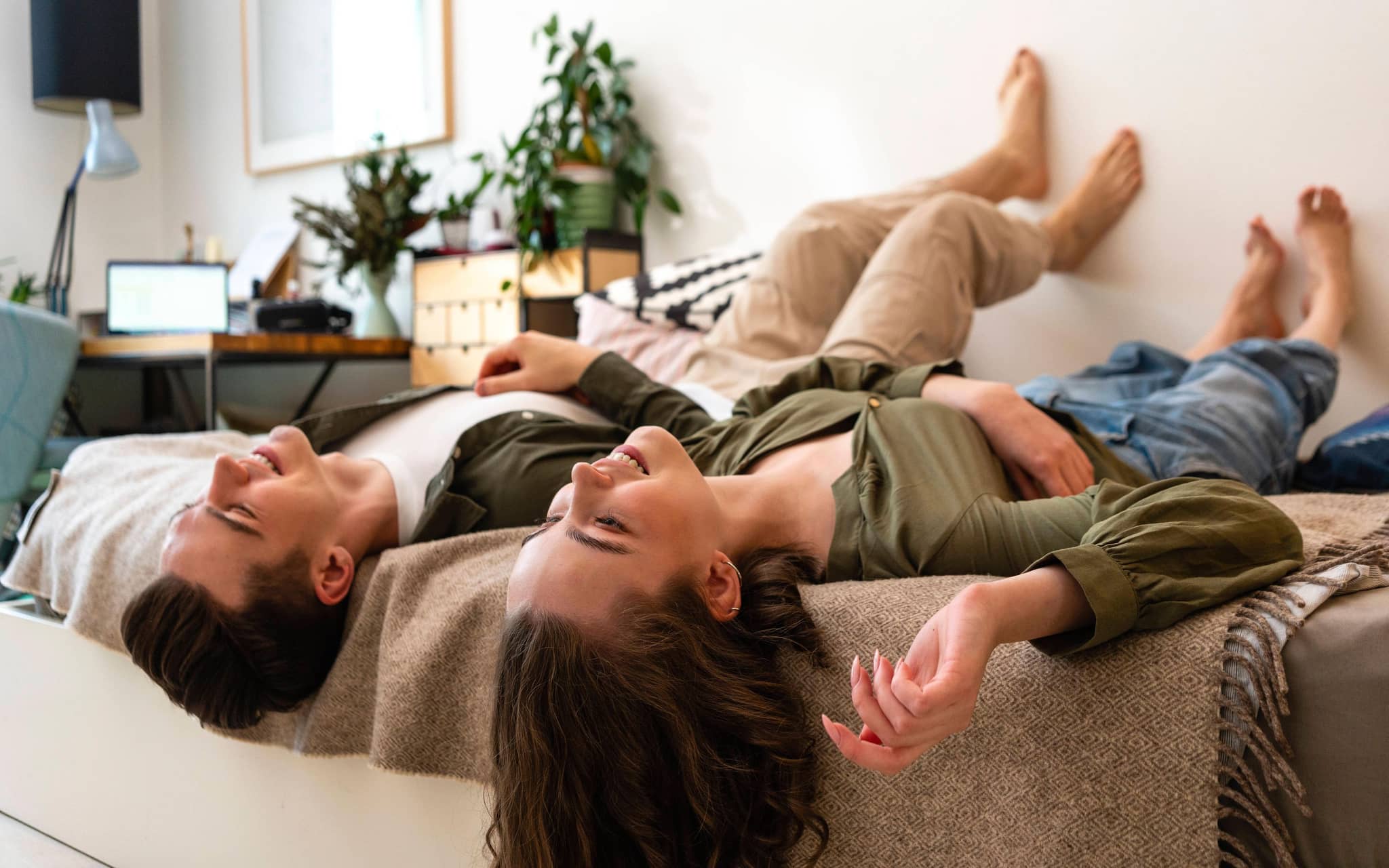 Junge und Mädchen liegen bekleidet nebeneinander im Bett und gucken vergnügt an die Decke