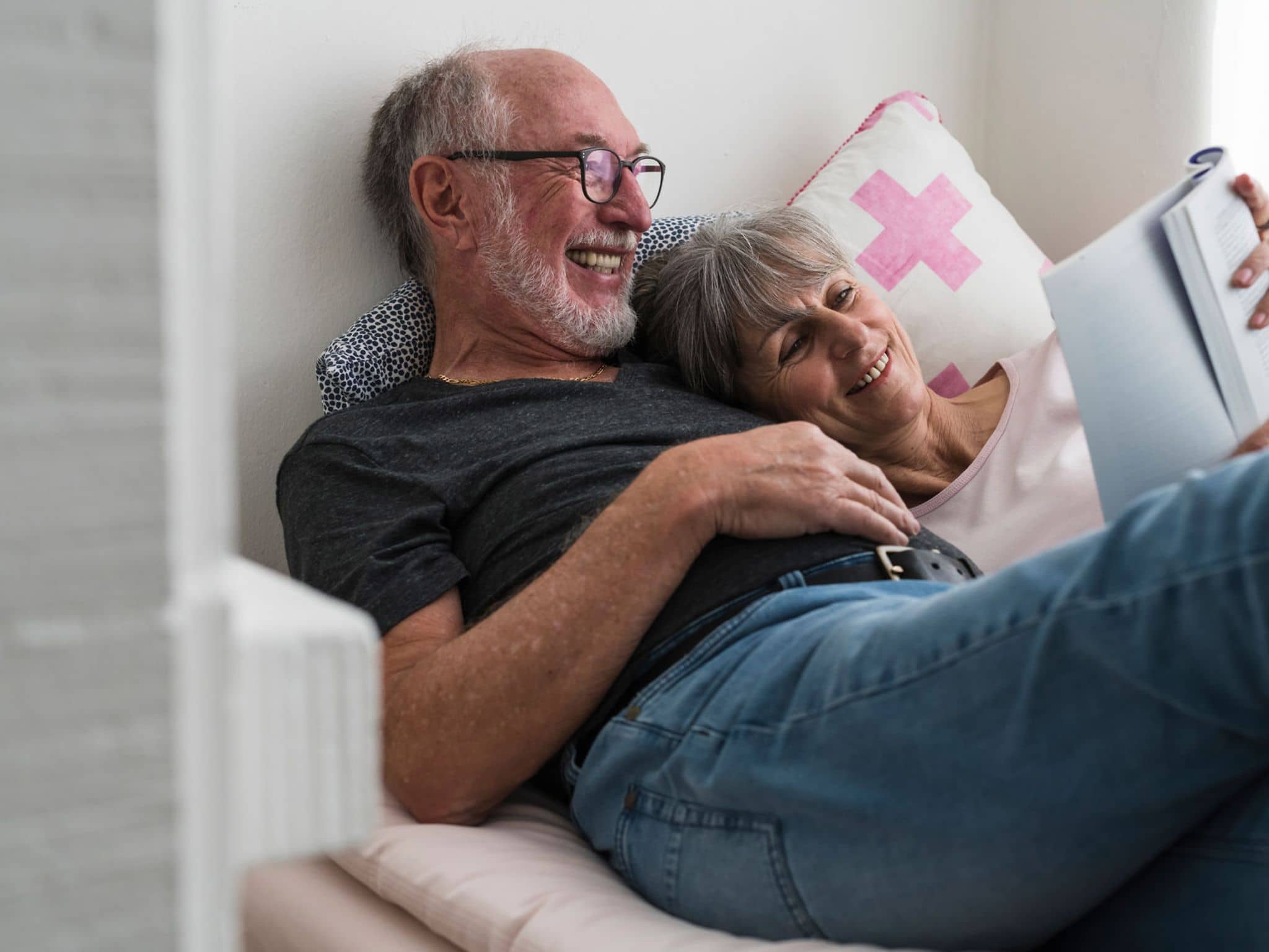 Krebsvorsorge: Glückliches älteres Paar liest gemeinsam ein Buch.