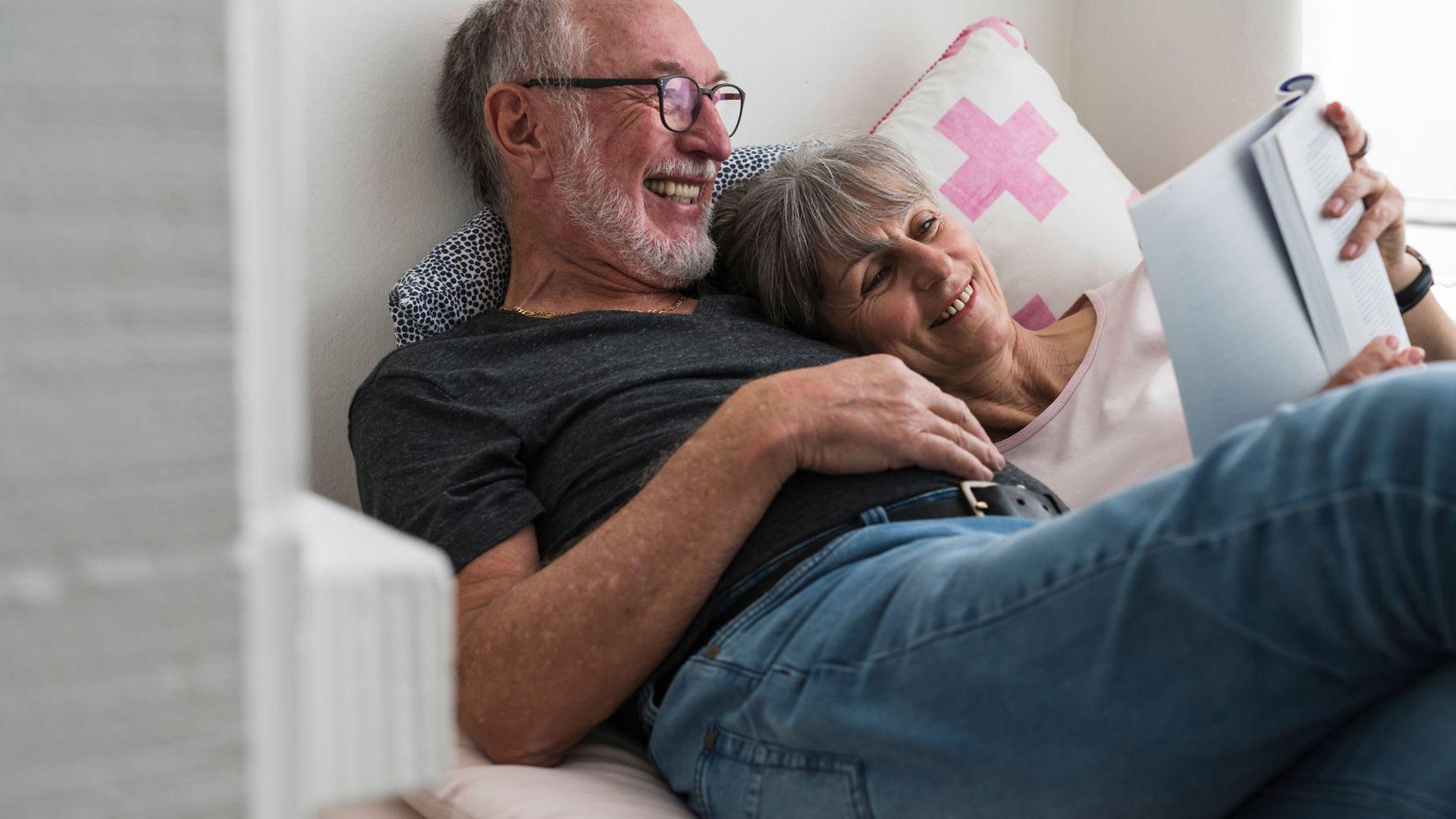 Krebsvorsorge: Glückliches älteres Paar liest gemeinsam ein Buch.