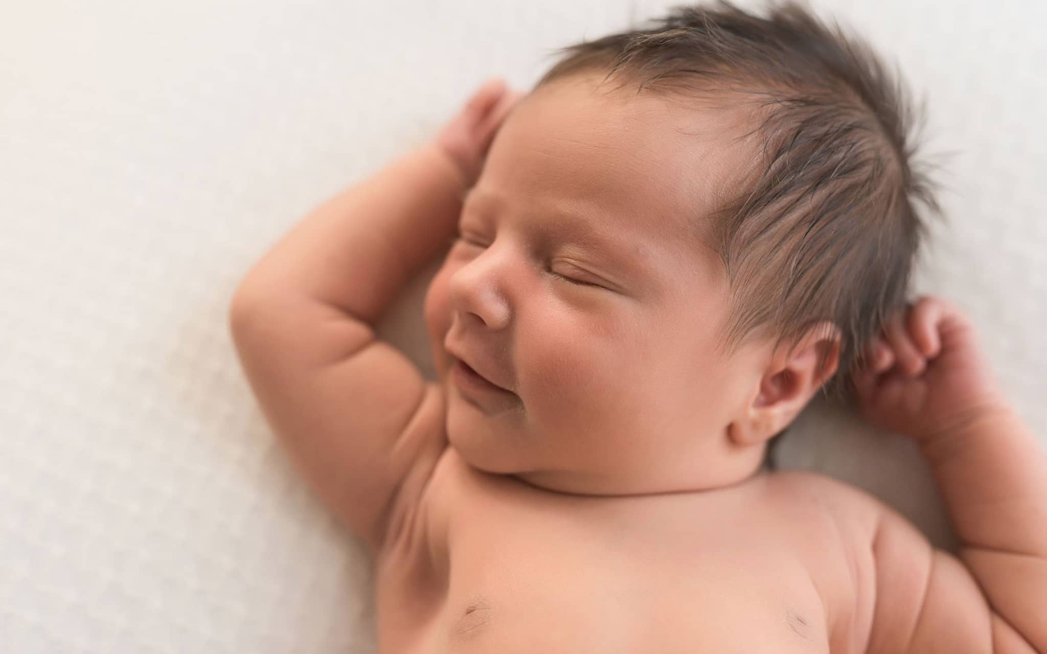 U2 Untersuchung: Ein schwarzhaariges Baby streckt sich im Liegen.