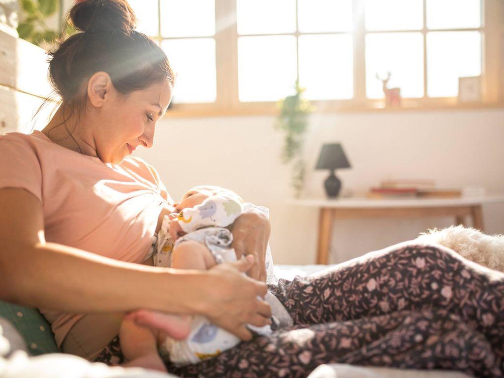 U3 Vorsorgeuntersuchung: Mutter stillt ihr Baby im Bett