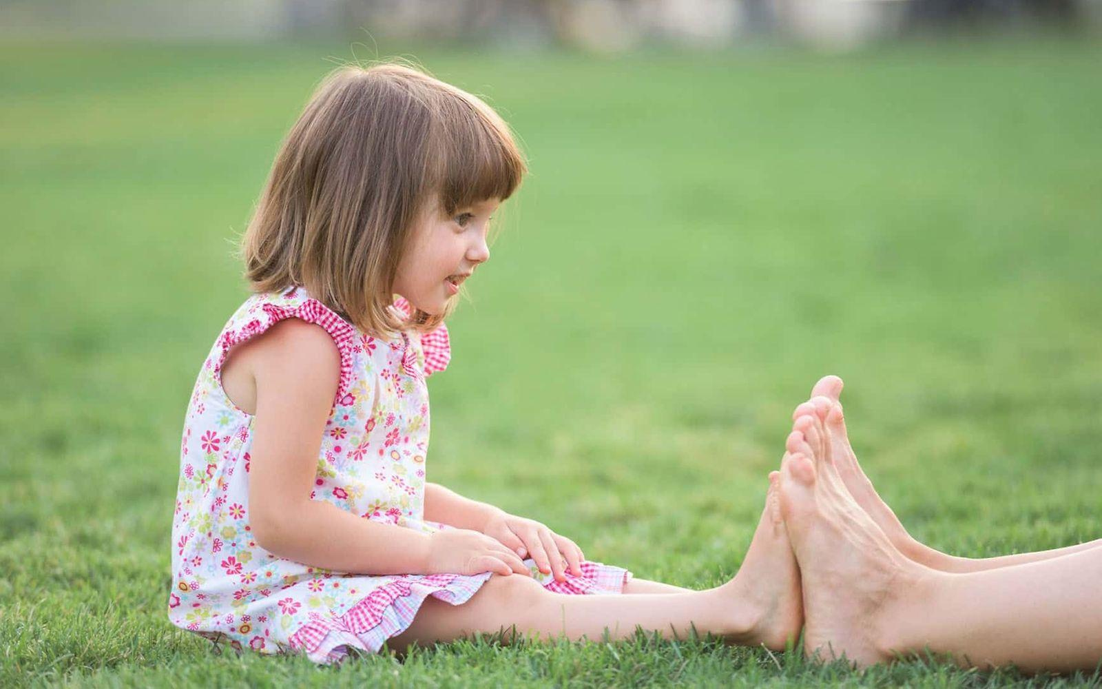 U7A Untersuchung: Ein kleines Mädchen vergleicht die Größe ihrer Füße mit der eines Erwachsenen.