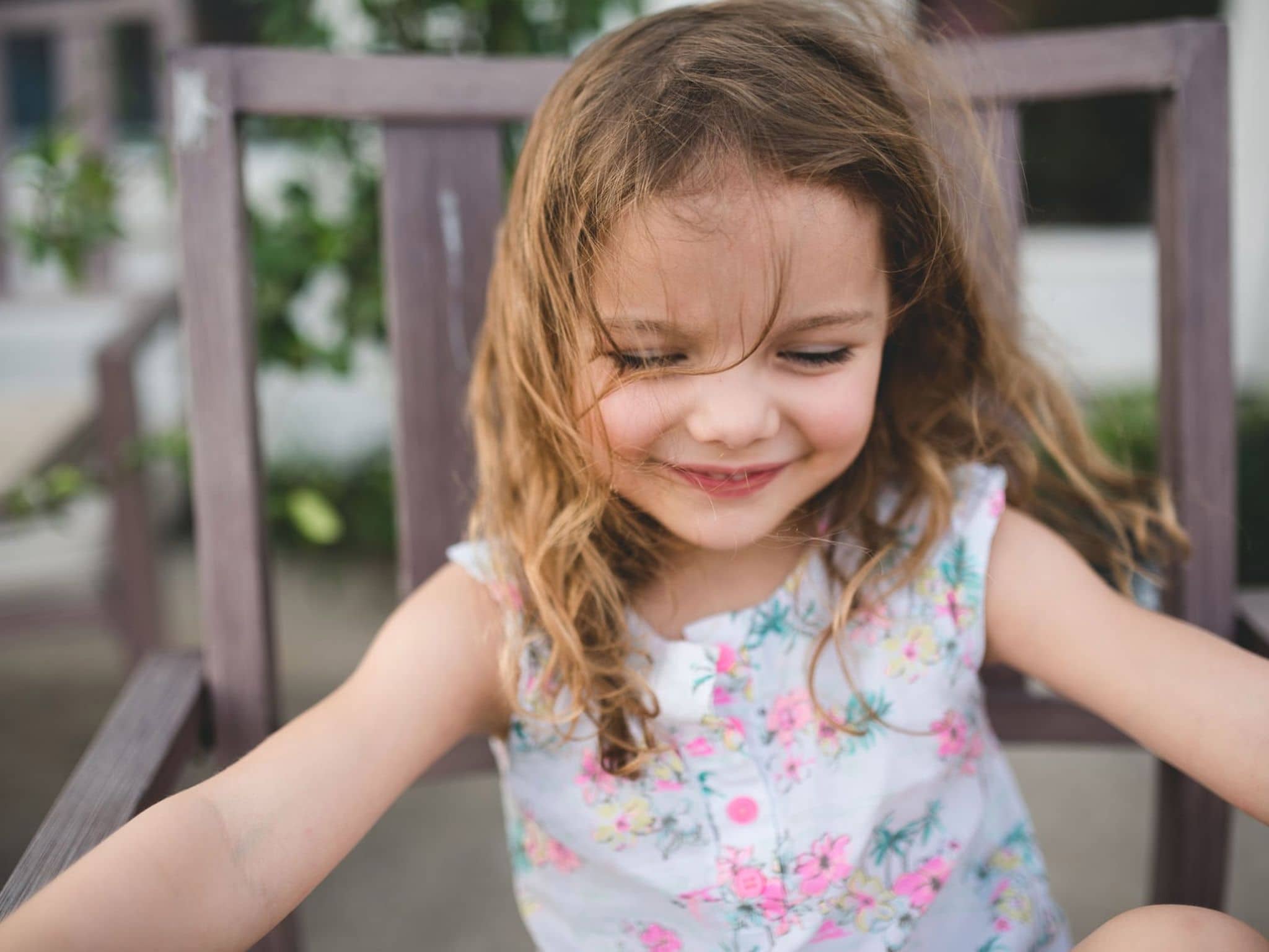 U9 Untersuchung: Kleines sitzendes Mädchen kneift ihre Augen zusammen und hat Spaß.