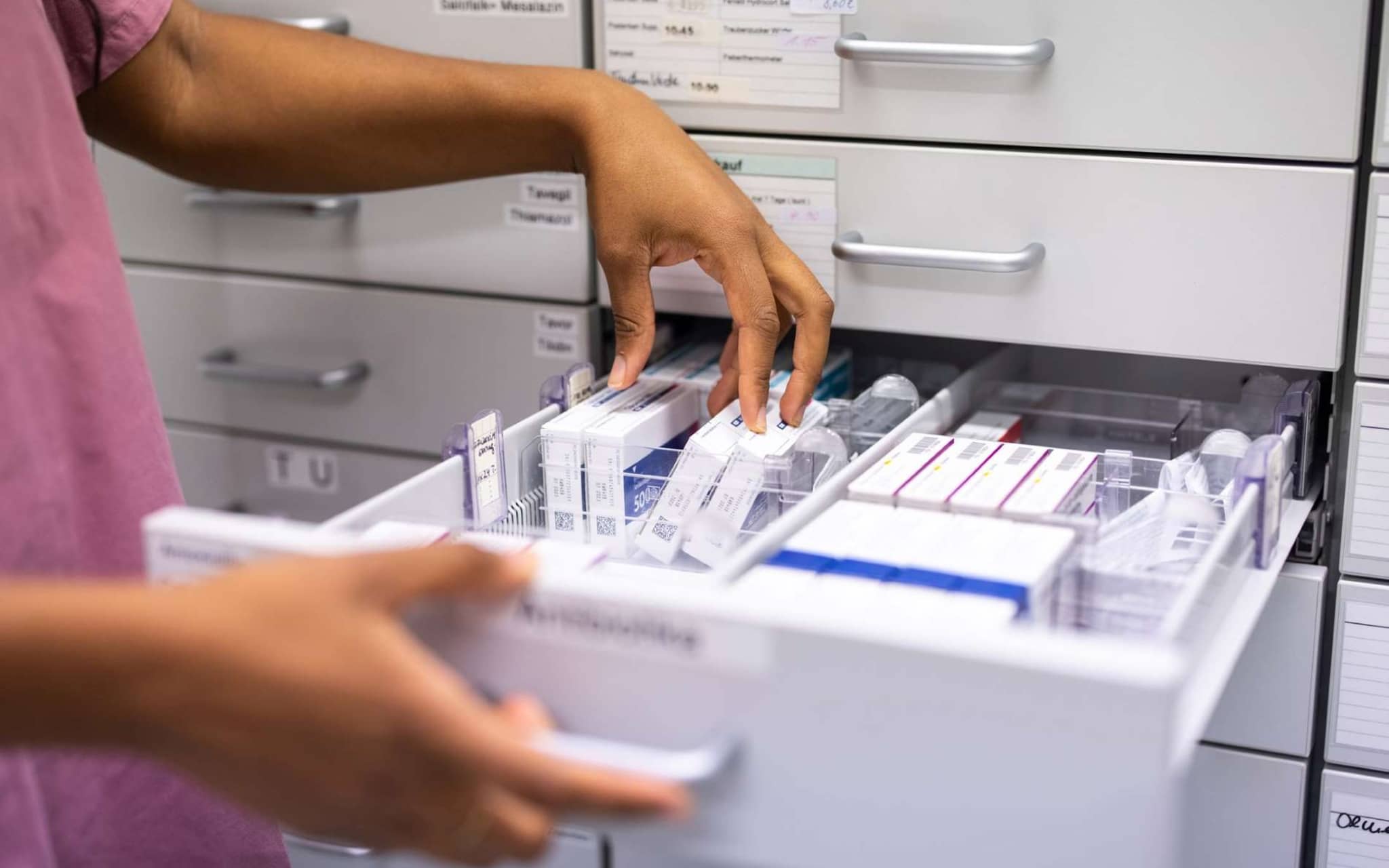 Arzneimittel auf Rabatt: Hände sortieren Medikamente in Schublade.
